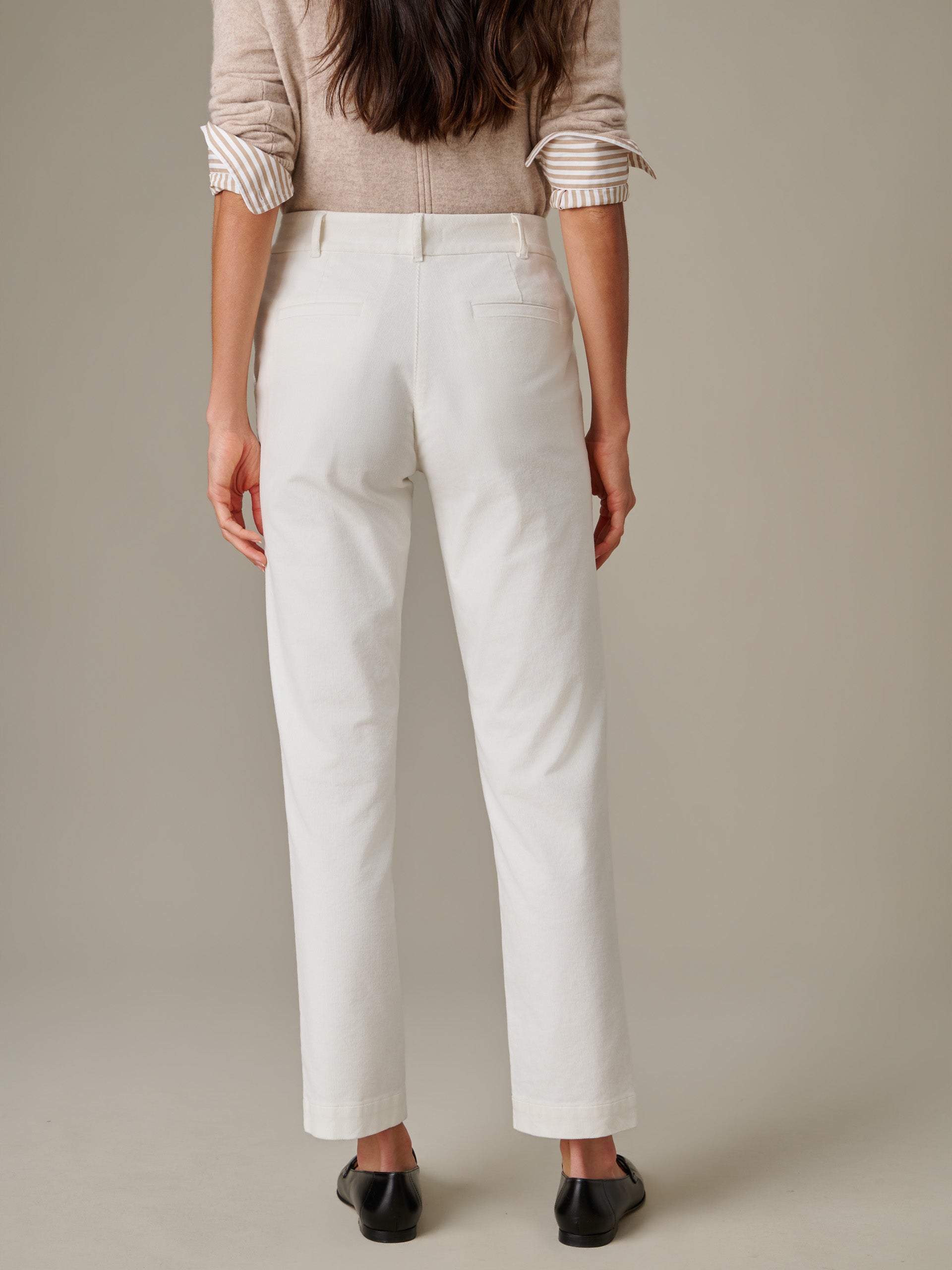 Rear view of a woman wearing off-white Avery Corduroy Pants by J.McLaughlin paired with a beige sweater, showcasing a timeless and effortlessly stylish look for enduring fashion.