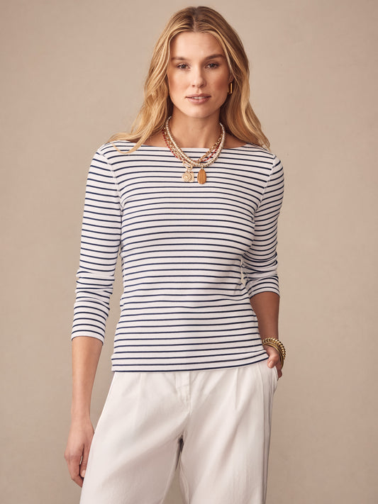 Woman wearing J.McLaughlin Goldie Tee in Stripe, a classic white and navy striped top paired with white pants, showcasing effortlessly stylish, enduring designs and innovative fabrics.