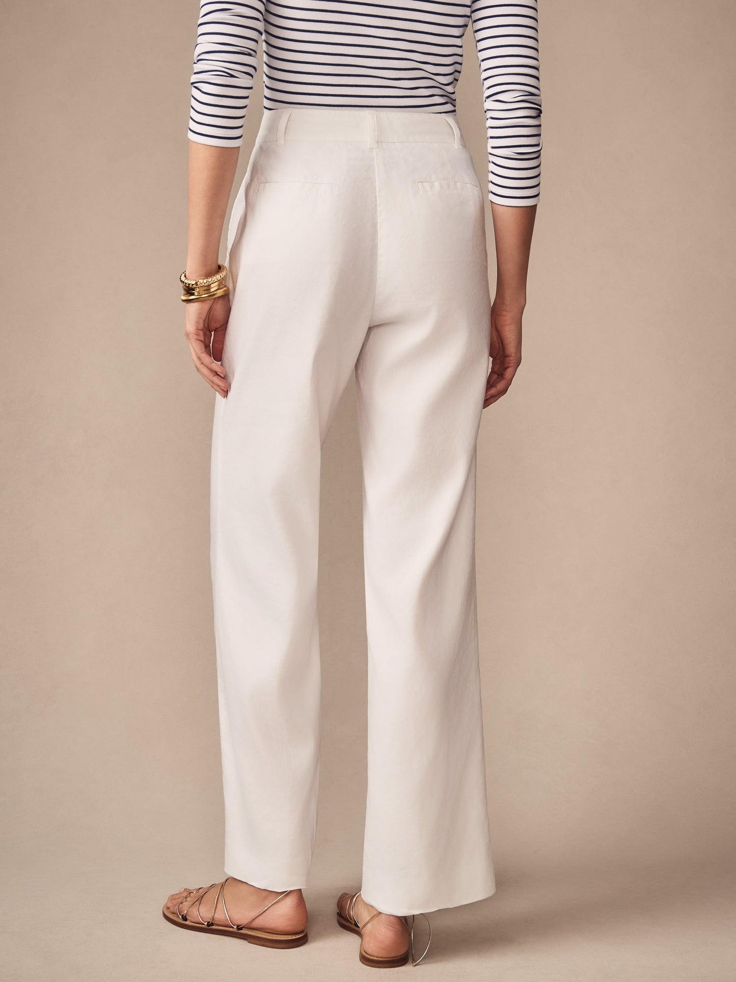 Woman wearing white Fiona Linen Blend Pants by J.McLaughlin paired with a striped top and gold bracelets, showcasing effortlessly stylish design and enduring appeal in classic wool-blend fabric.