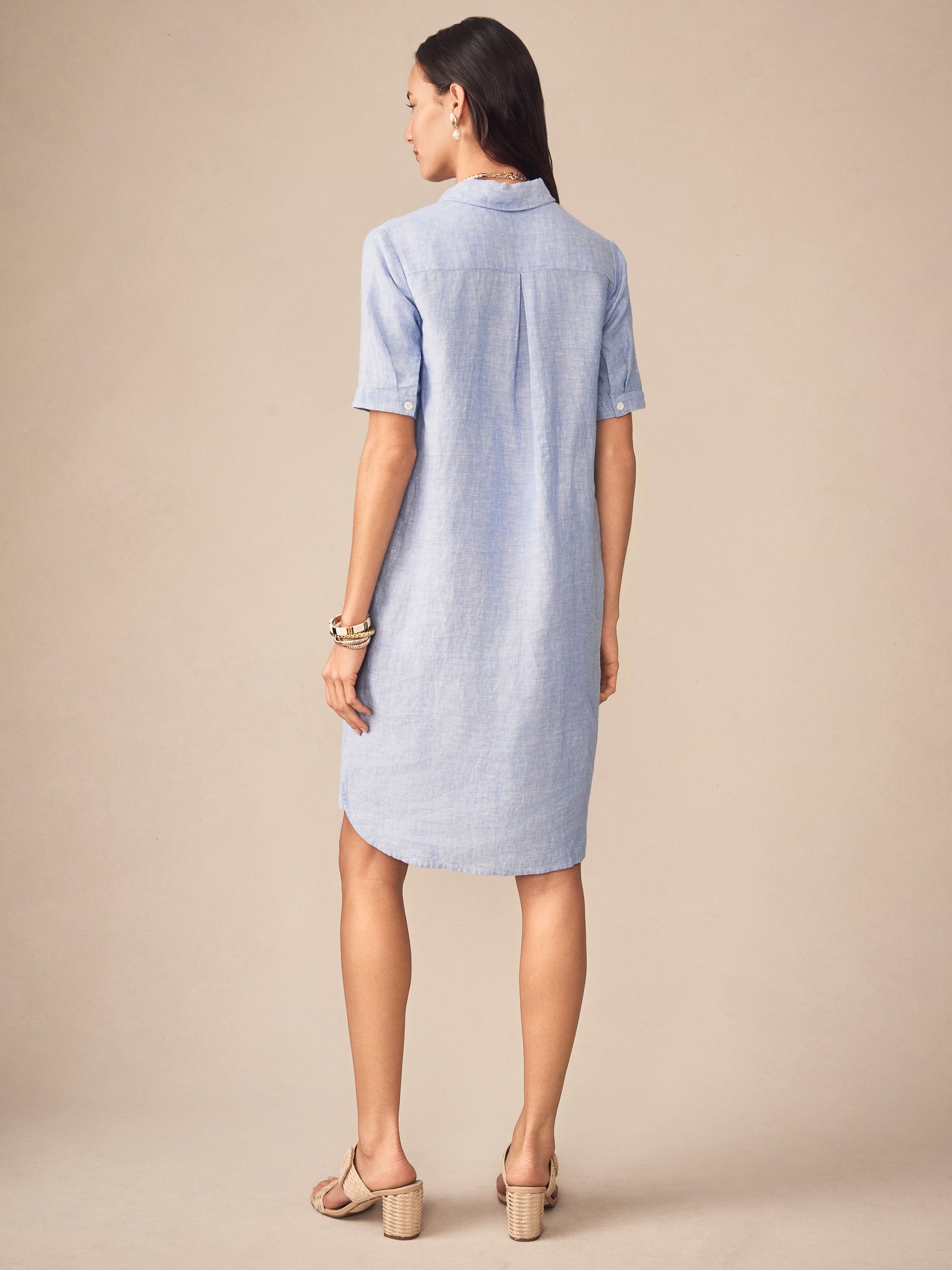 A woman wearing the Arissa Linen Dress by J.McLaughlin in a soft blue tone, showcasing effortlessly stylish, enduring designs with innovative fabrics for a destination defining style. Life, Well-Lived.