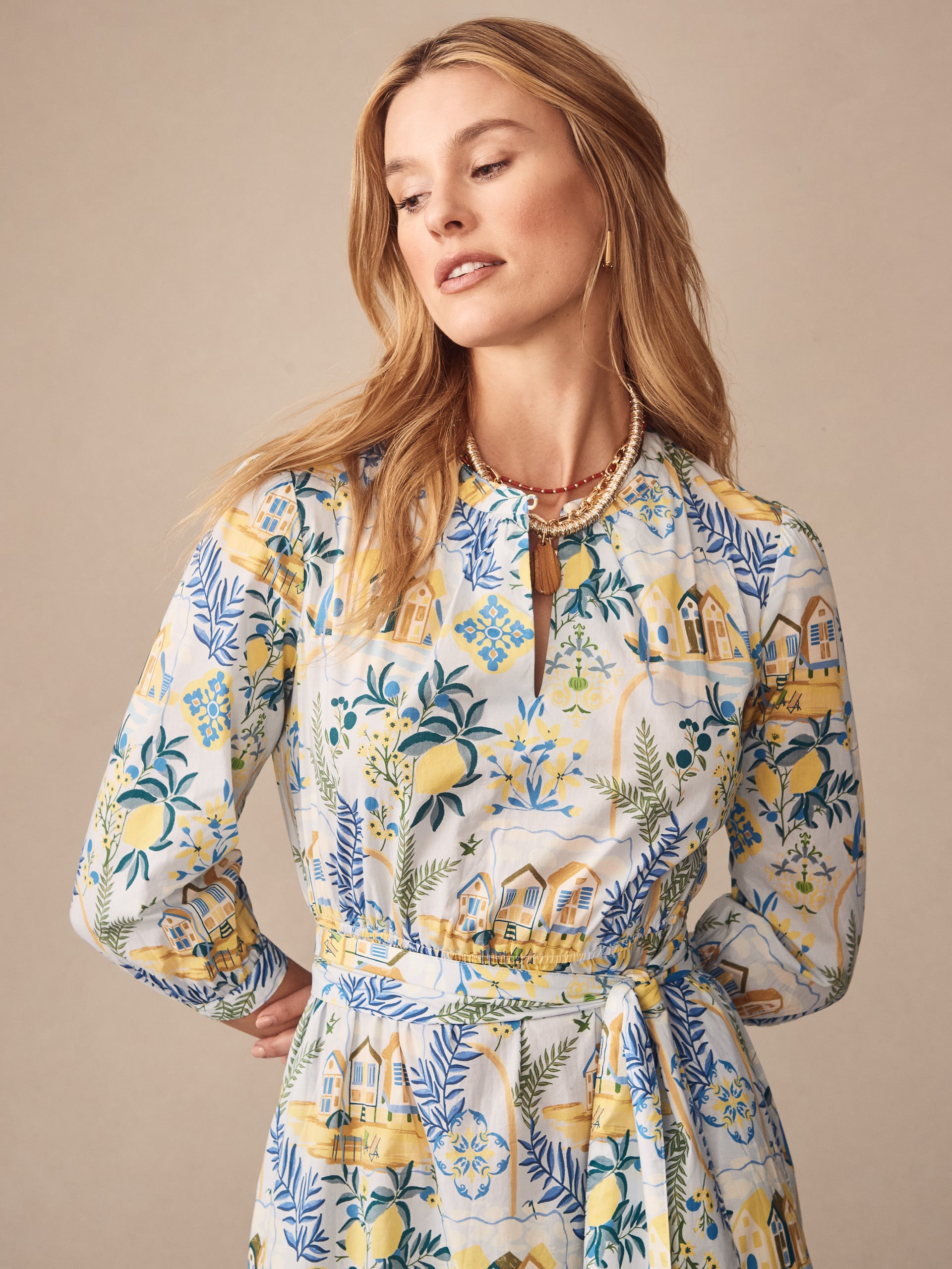 Woman wearing the Cerina Dress in Amalfi Coast by J.McLaughlin, featuring an effortlessly stylish pattern with blue, yellow, and green tones, showcasing enduring designs and innovative fabrics.