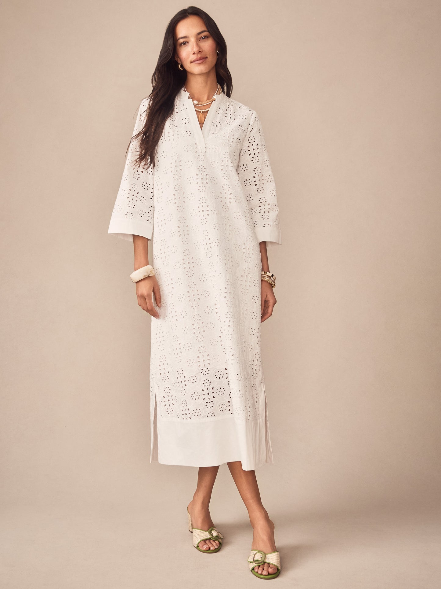 Woman wearing J.McLaughlin Cindy Eyelet Dress in off-white, featuring intricate eyelet details, paired with accessories for an effortlessly stylish look embodying enduring designs and timeless fashion.