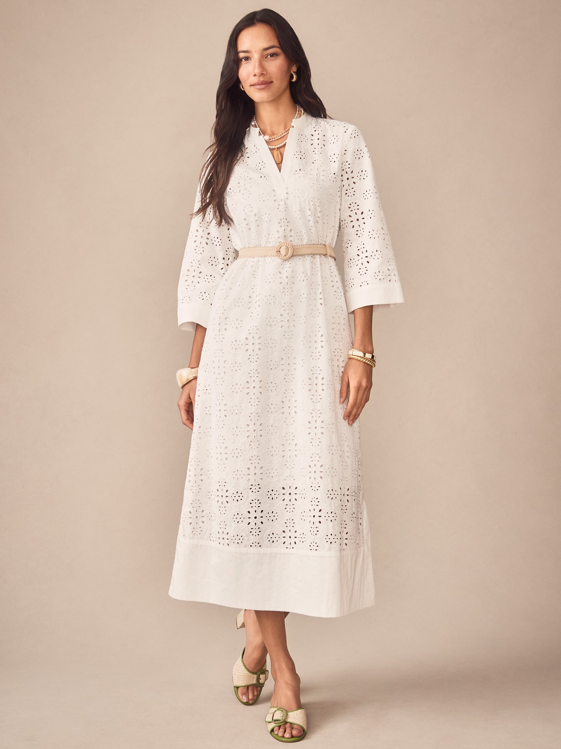 A woman wearing the Cindy Eyelet Dress by J.McLaughlin, featuring delicate eyelet fabric and a beige belt, showcasing effortlessly stylish and enduring designs for a life well-lived.