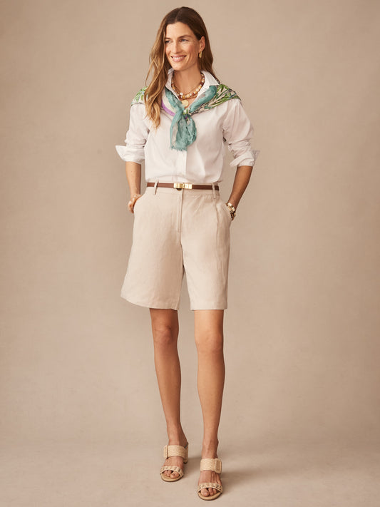 Woman wearing Cooper Linen Blend Shorts in a light stone color styled with a white button-down shirt, a green patterned scarf, and beige sandals, showcasing J.McLaughlin’s effortlessly stylish, enduring designs in innovative fabrics, a destination for defining style. Life, Well-Lived.