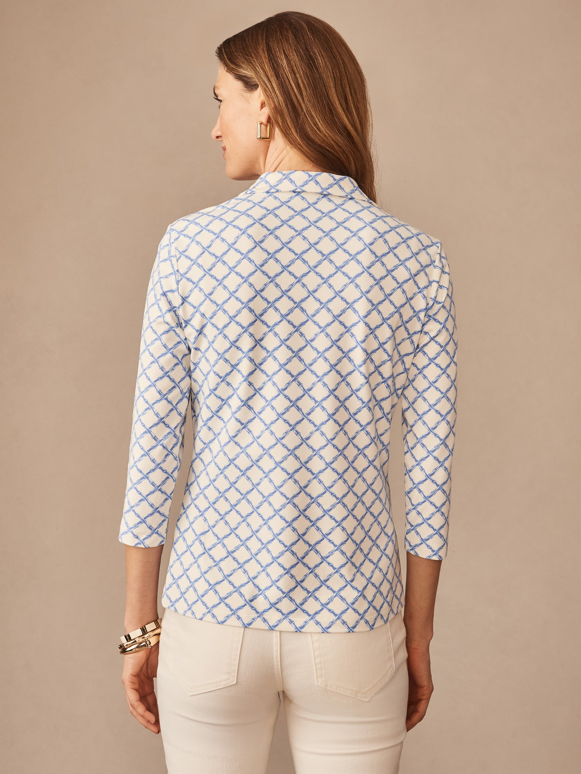 Woman seen from the back wearing the Court 3/4 Sleeve Polo in Micro Bamboo by J.McLaughlin, featuring a blue lattice pattern on off-white fabric, effortlessly stylish with enduring designs.