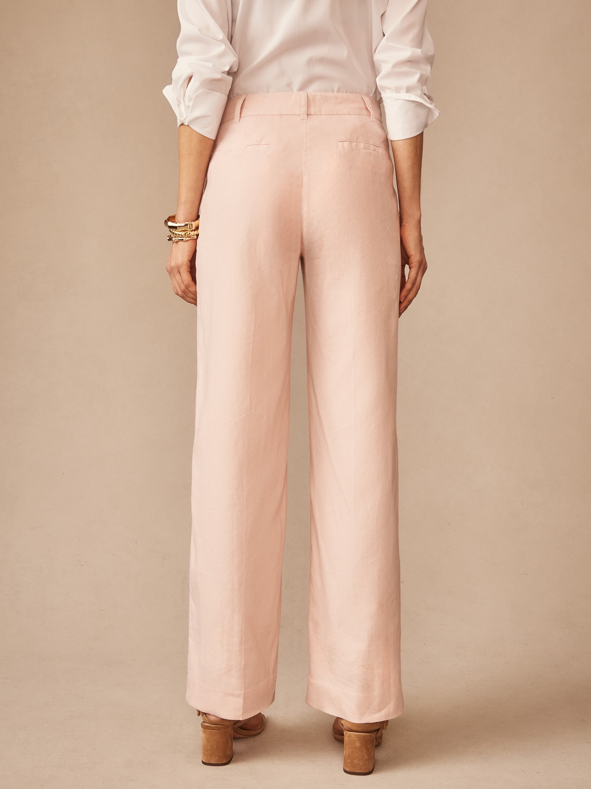 Back view of a model wearing pale pink Fiona Linen Blend Pants by J.McLaughlin, paired with a white shirt and tan heels, showcasing effortlessly stylish, enduring designs with a legacy of timeless fashion.