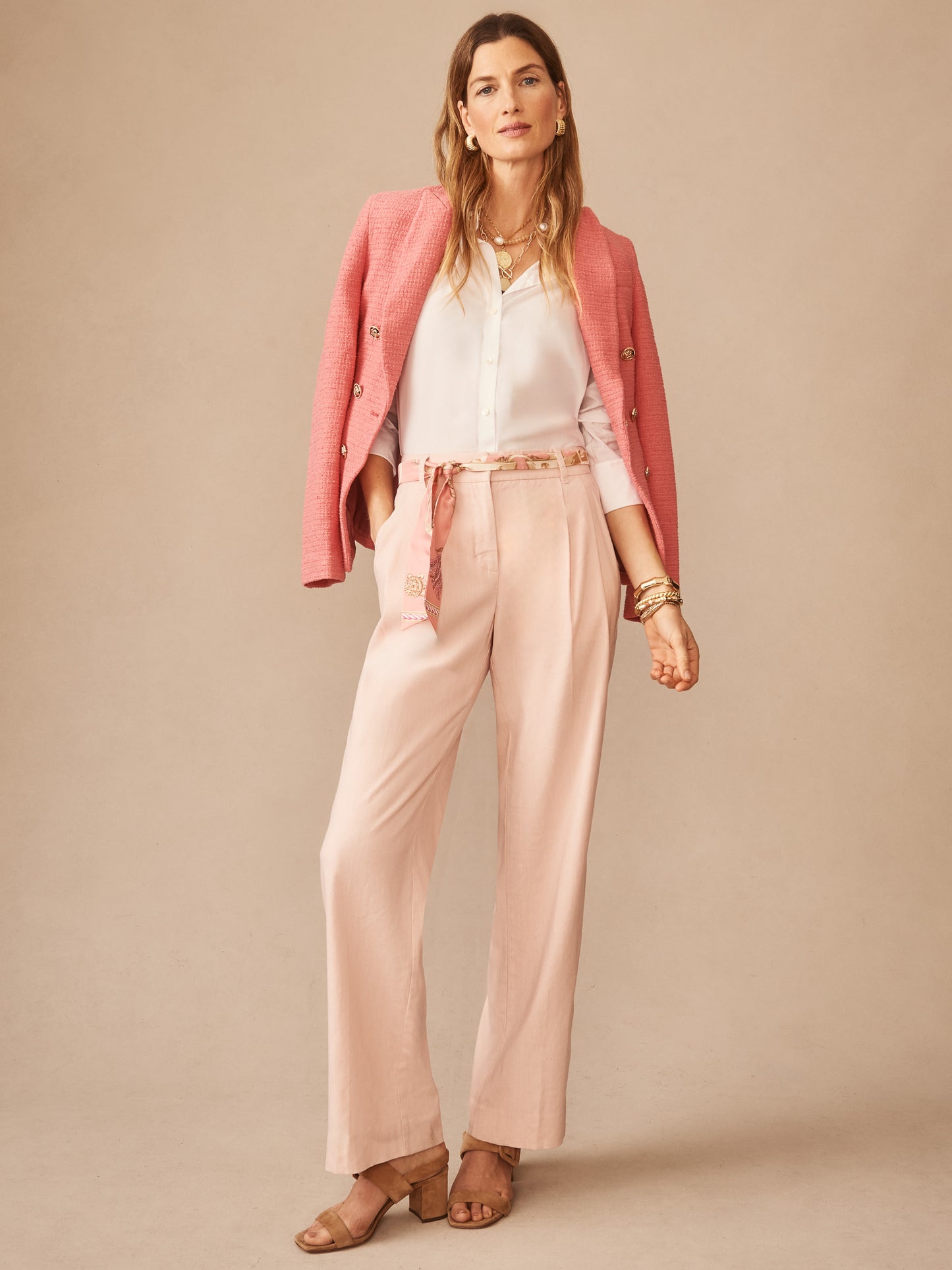 Woman wearing J.McLaughlin Fiona Linen Blend Pants styled with a white blouse and pink blazer draped over shoulders, embodying effortlessly stylish, enduring designs with innovative fabrics.