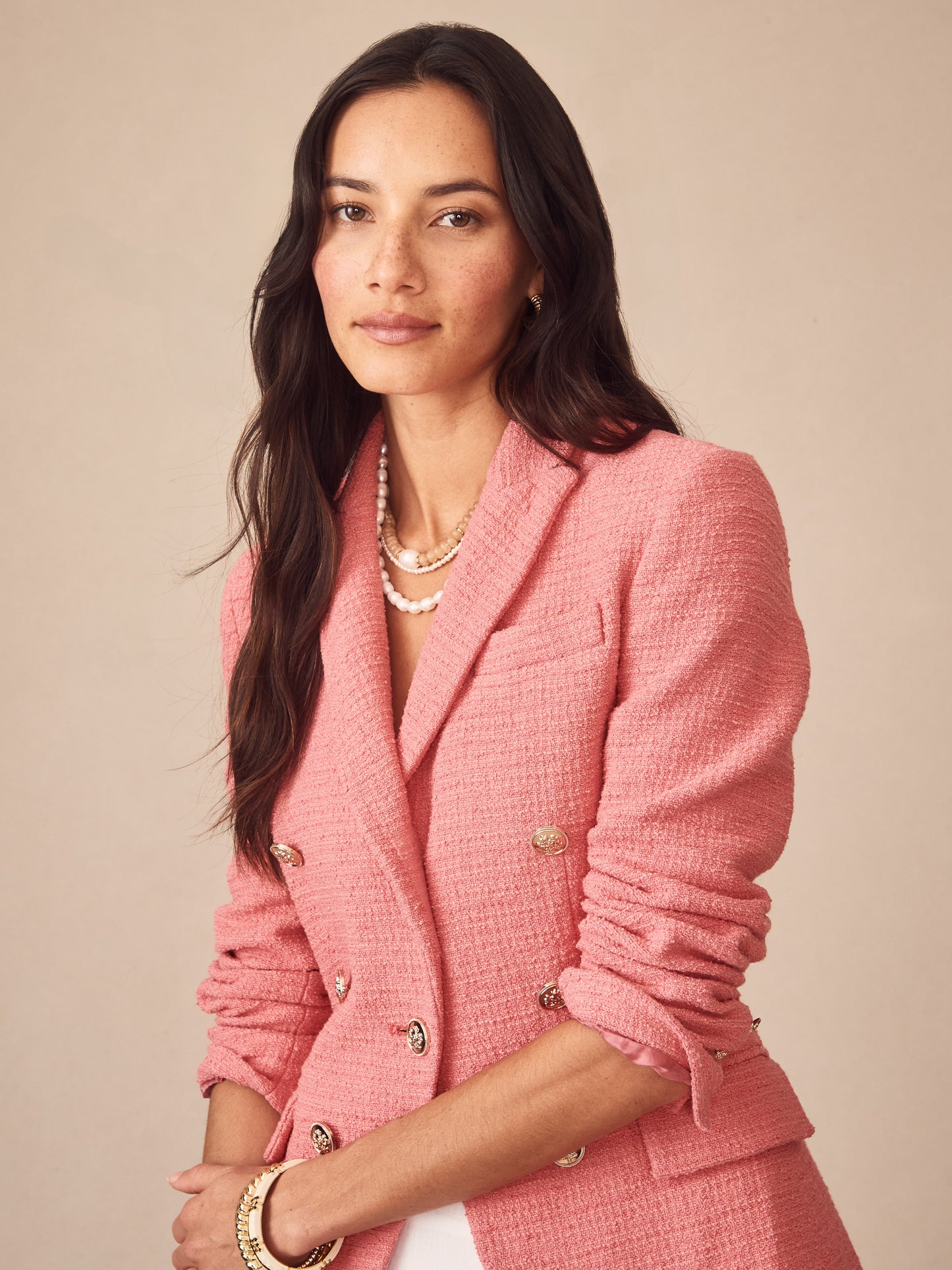 A woman wearing a pink Genevieve Cotton Bouclé Blazer by J.McLaughlin, showcasing effortlessly stylish, enduring designs with innovative fabrics and a legacy of timeless fashion.