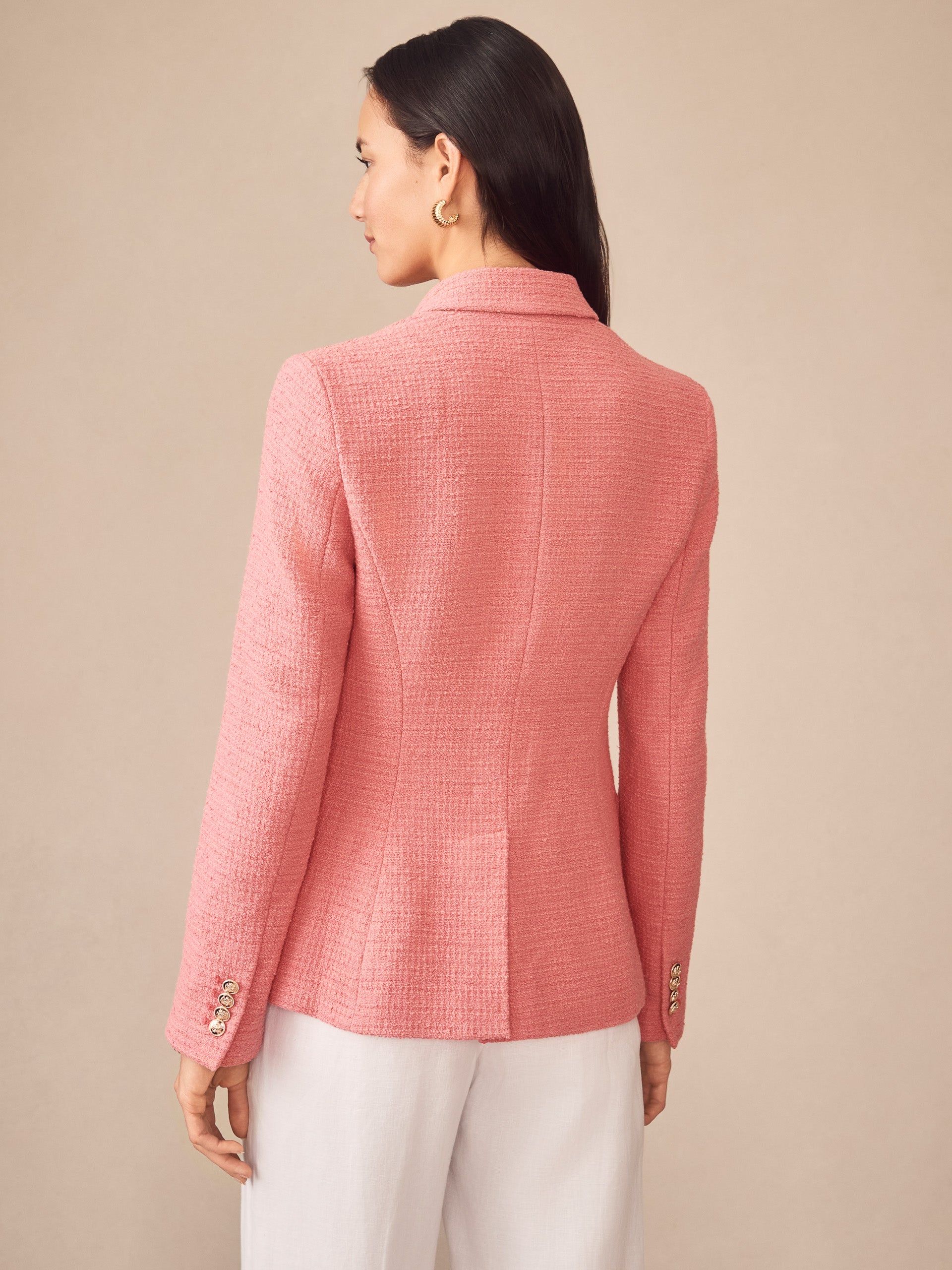 A woman models the back of the effortlessly stylish Genevieve Cotton Bouclé Blazer in soft pink by J.McLaughlin, showcasing enduring designs and innovative fabrics.