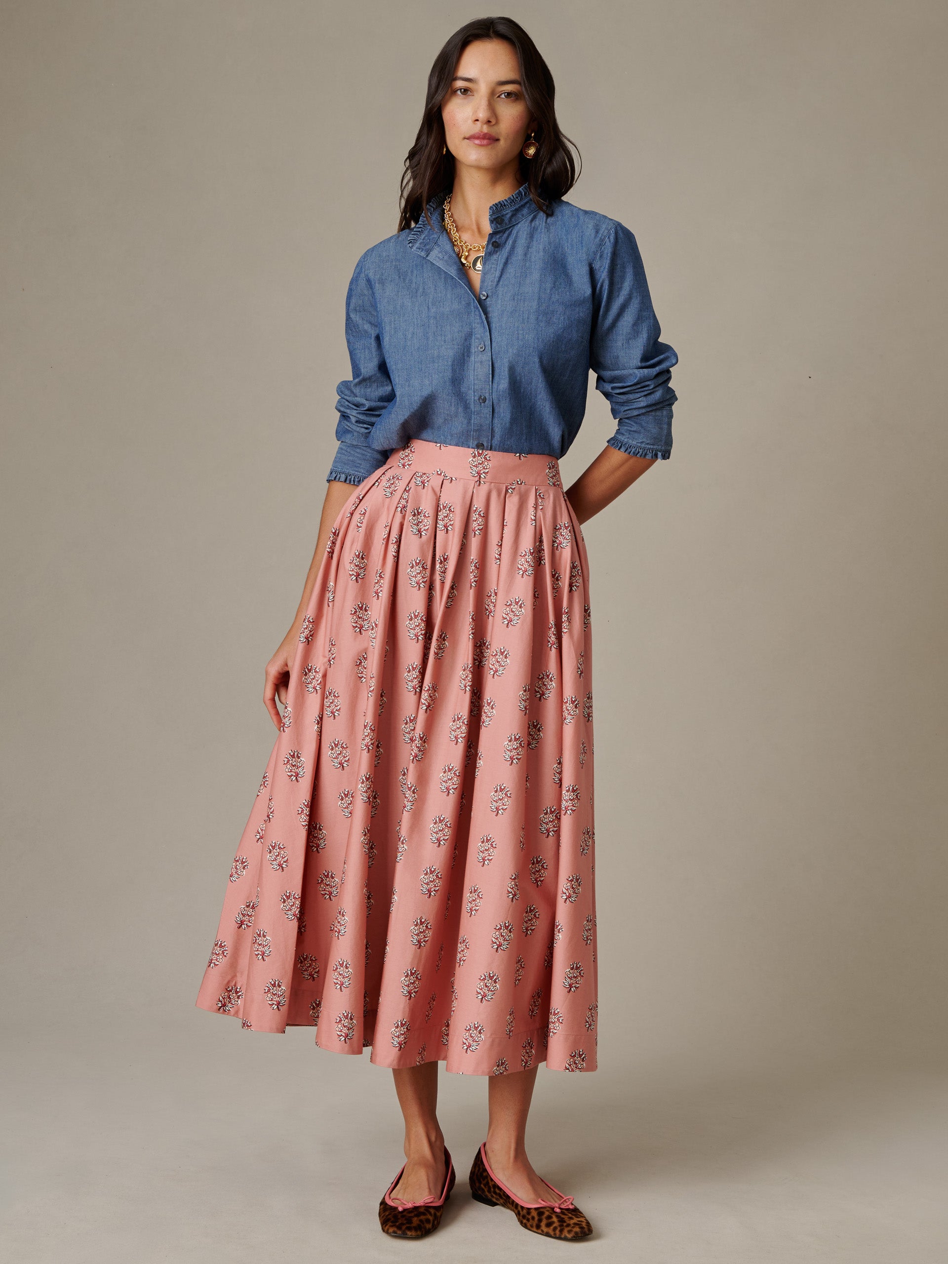 Woman wearing a blue button-up blouse paired with the Arabella Skirt in Heritage Bloom Cross by J.McLaughlin, featuring a soft pink floral pattern and relaxed fit.