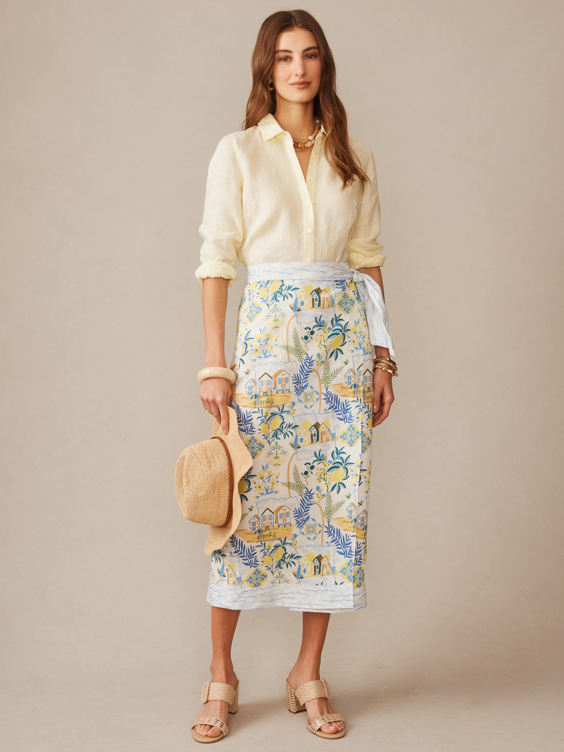 A woman models the Ardis Linen Blend Skirt in Amalfi Coast by J.McLaughlin, paired with a light cream blouse, showcasing effortlessly stylish, enduring designs with innovative fabrics. A destination for defining style. Life, Well-Lived.