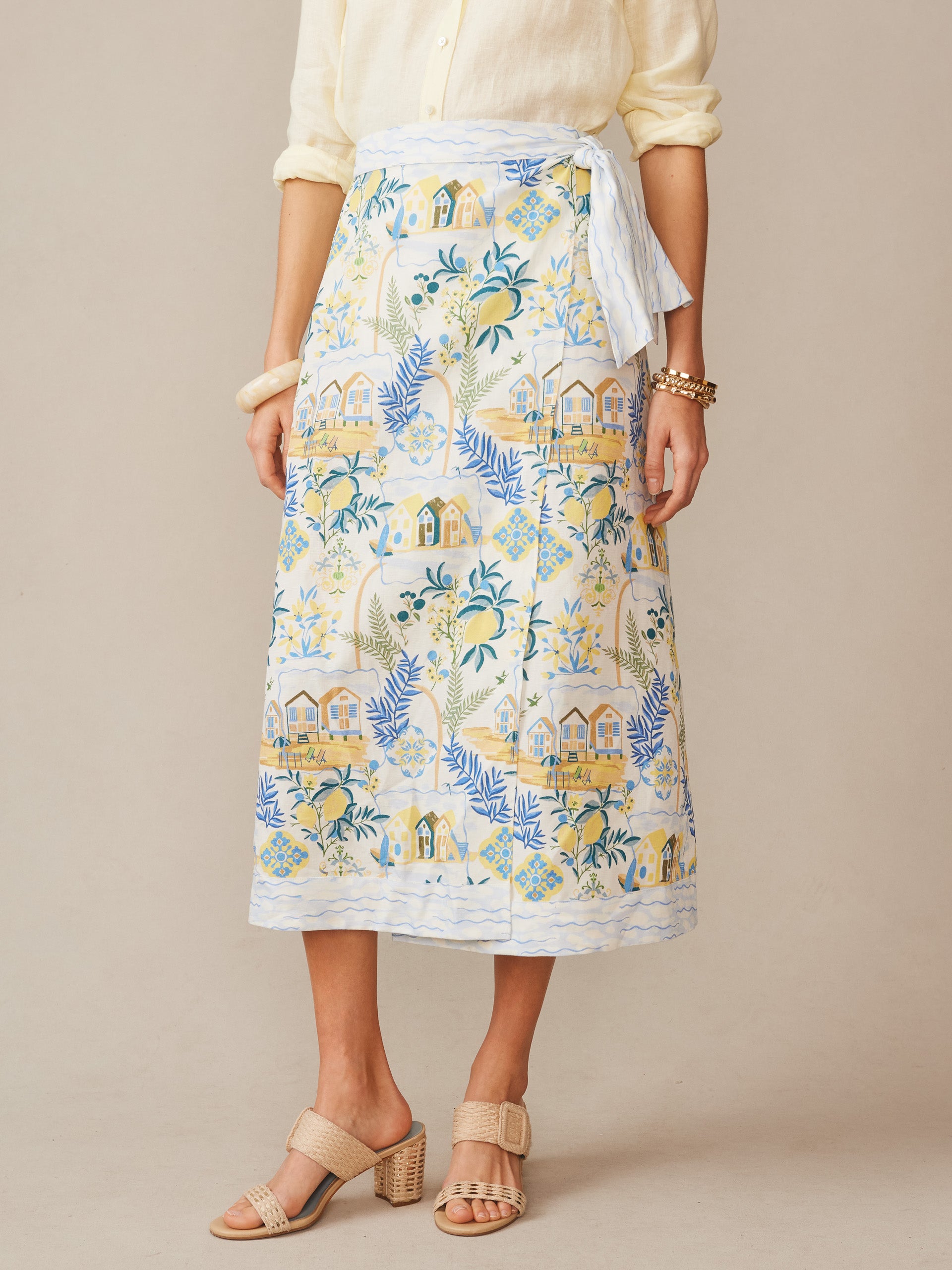 A woman wears the Ardis Linen Blend Skirt in Amalfi Coast by J.McLaughlin, featuring an effortlessly stylish pattern in soft blue, yellow, and off-white tones, embodying enduring designs and a legacy of timeless fashion. A destination for defining style. Life, Well-Lived.