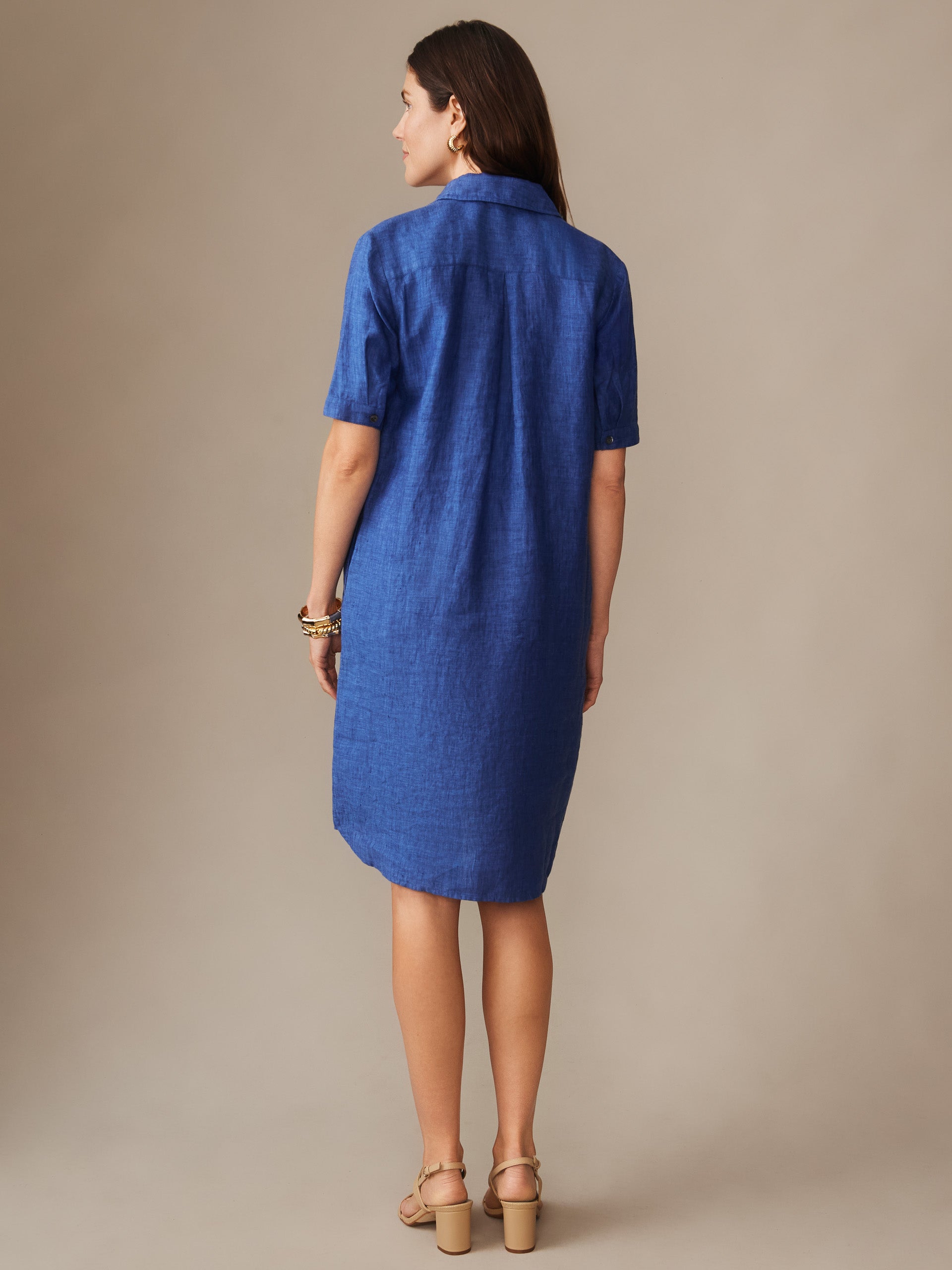 Woman seen from behind wearing a cobalt blue Arissa Linen Dress by J.McLaughlin, featuring short sleeves and a classic collar, embodying effortlessly stylish and enduring designs.