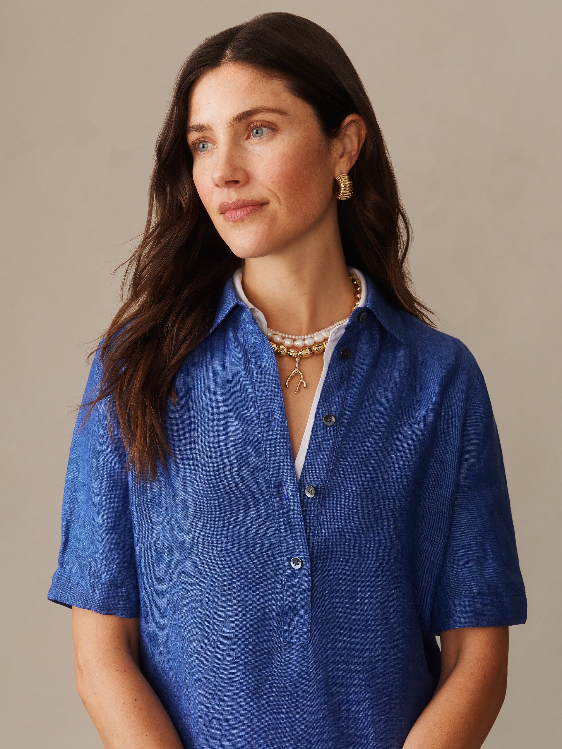 Woman wearing a denim blue Arissa Linen Dress by J.McLaughlin, showcasing effortlessly stylish, enduring designs crafted from innovative fabrics for a legacy of timeless fashion.
