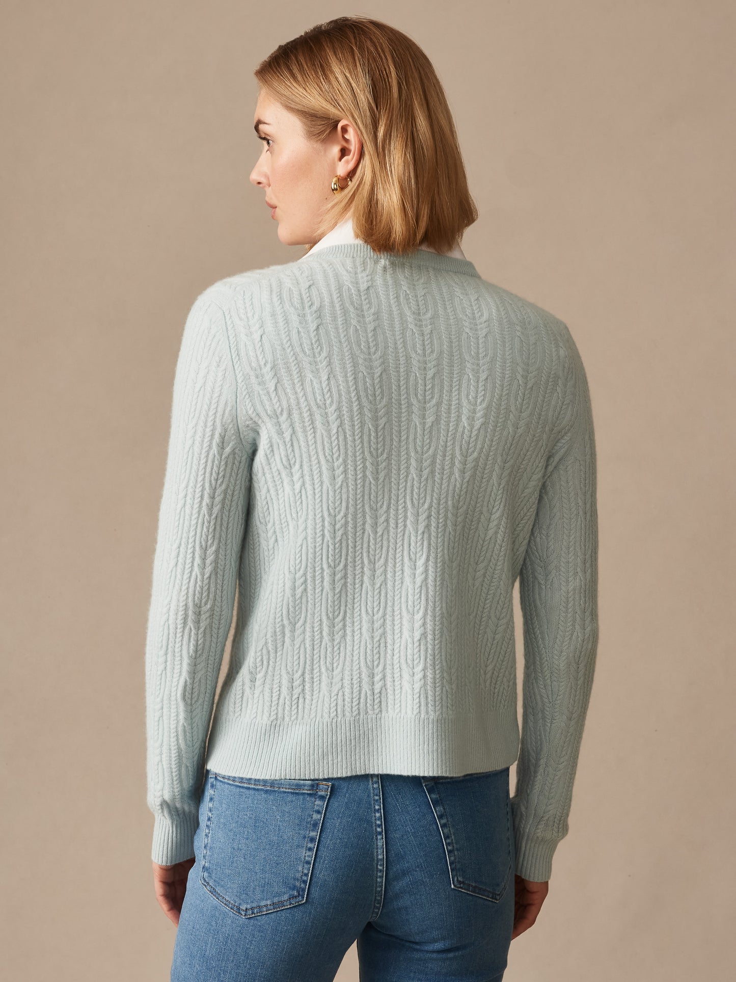 Woman wearing a soft aqua Ashby Cashmere Sweater from J.McLaughlin, featuring a cable knit design and embodying effortlessly stylish, enduring designs with a legacy of timeless fashion.