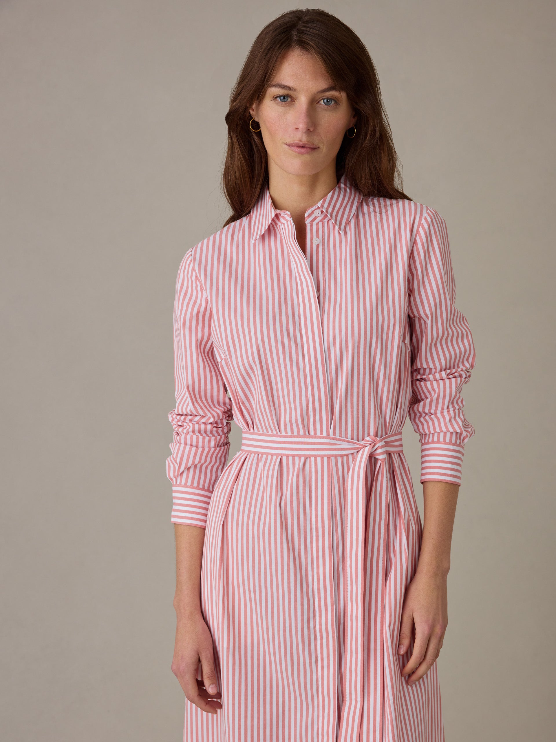 Woman wearing a Leighton Dress in Stripe by J.McLaughlin, featuring pink and white vertical stripes, long sleeves, and a waist tie for a timeless, effortlessly stylish look.
