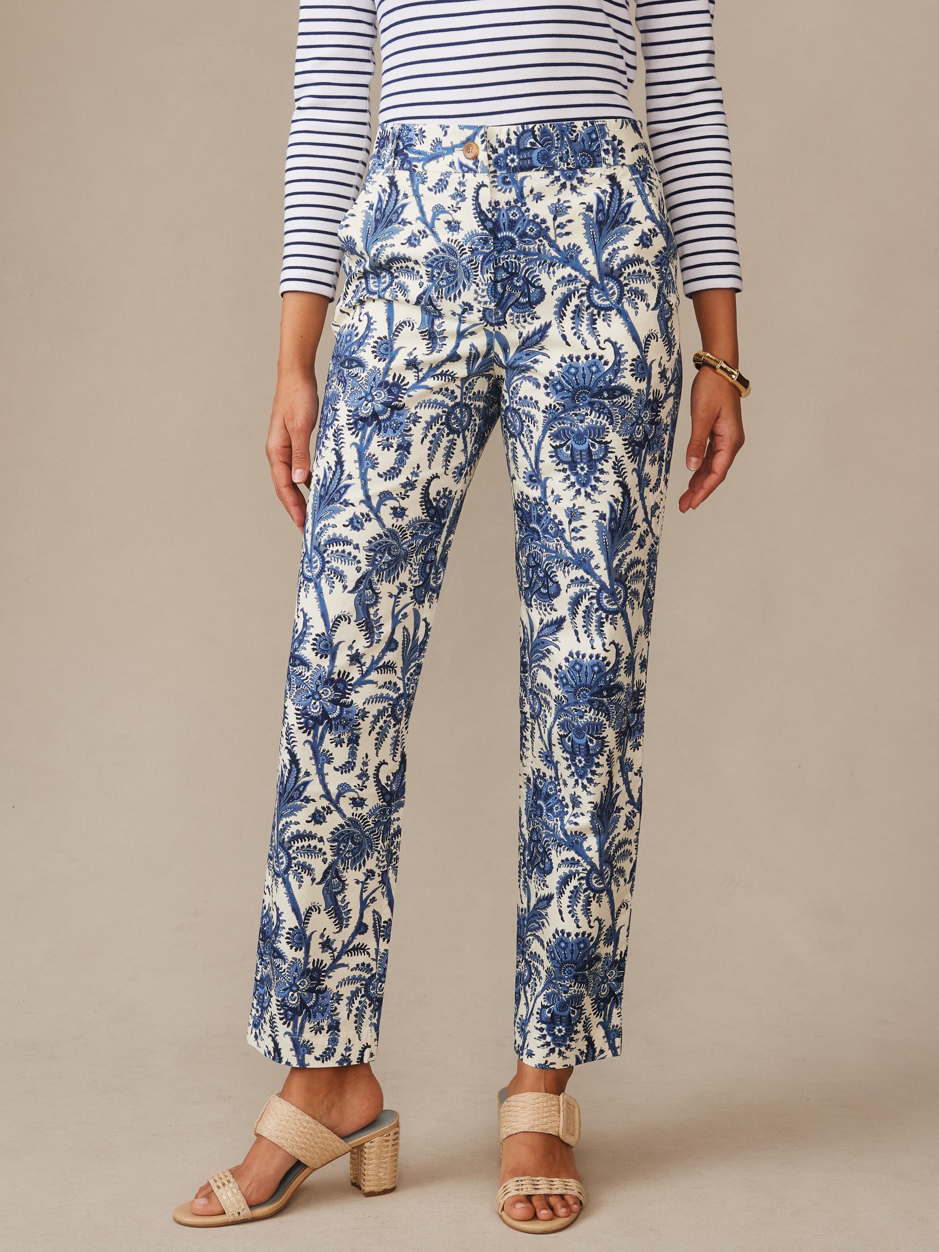 A woman models Avery Pants in Heirloom Paisley by J.McLaughlin, featuring a classic blue and cream paisley print paired with a striped top and woven sandals, epitomizing effortlessly stylish, enduring designs for a life well-lived.