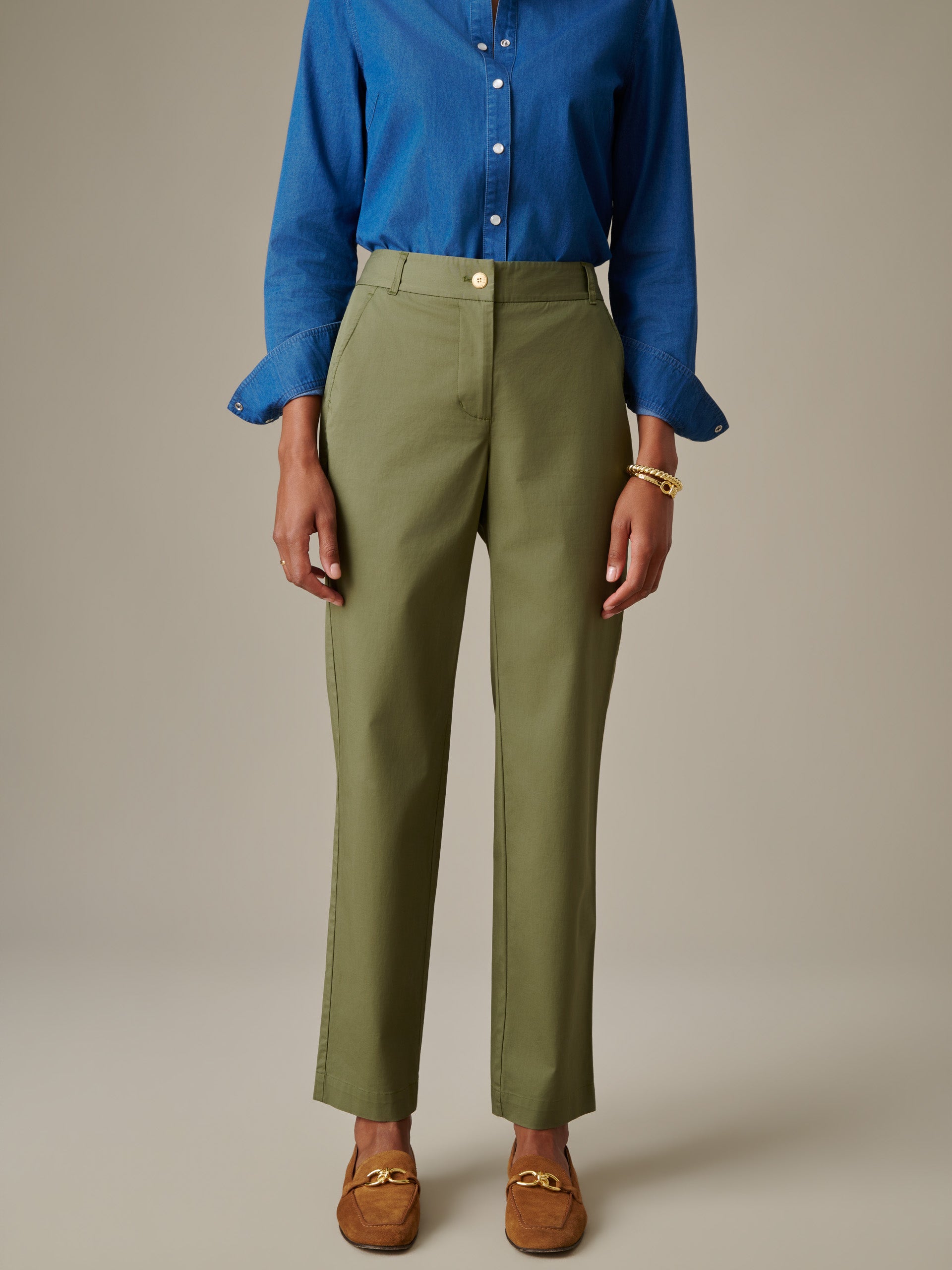 Front view of a person wearing olive green Avery Cotton Chino Pants styled with a blue button-up shirt and brown loafers by J.McLaughlin, showcasing enduring design and timeless style.