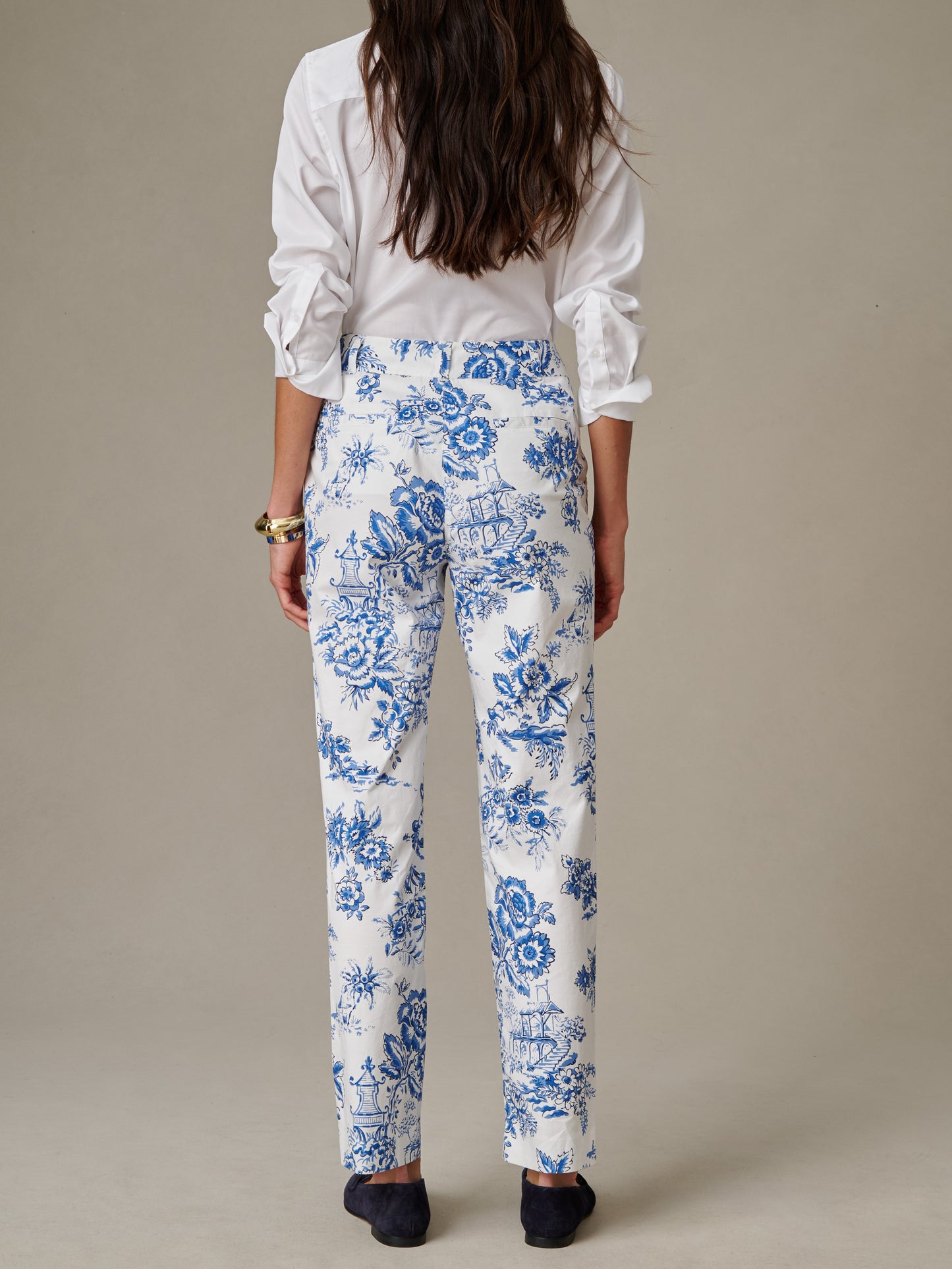 Rear view of a woman wearing Avery Pants in Antique Toile by J.McLaughlin, featuring a classic blue and white floral and nautical print, styled with a white shirt and black shoes.