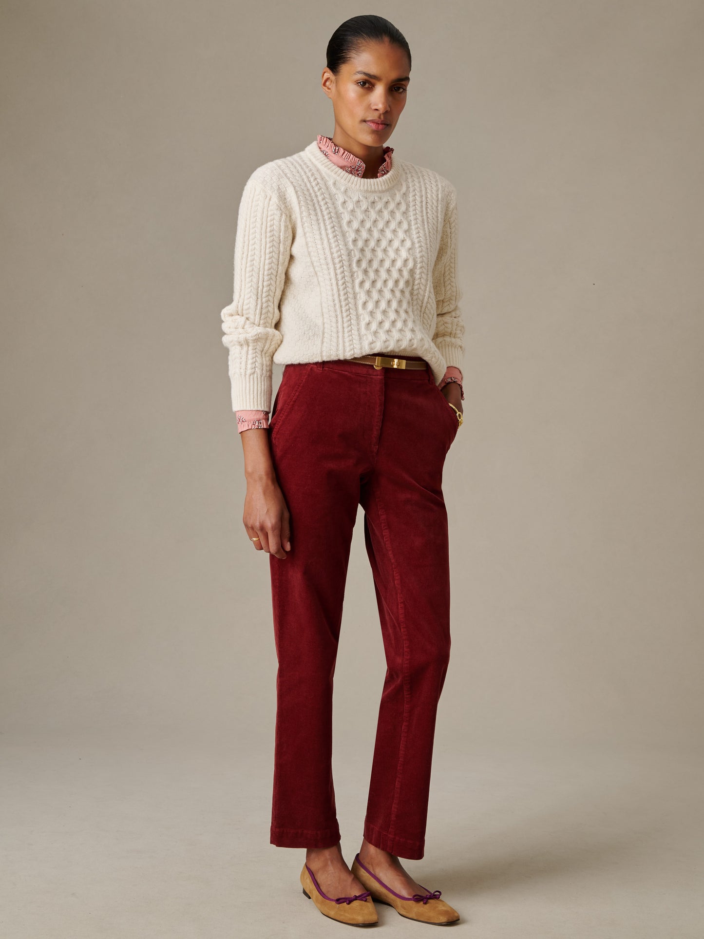 Woman wearing burgundy Avery Corduroy Pants by J.McLaughlin paired with a cream cable-knit sweater and loafers, showcasing effortlessly stylish and enduring designs.