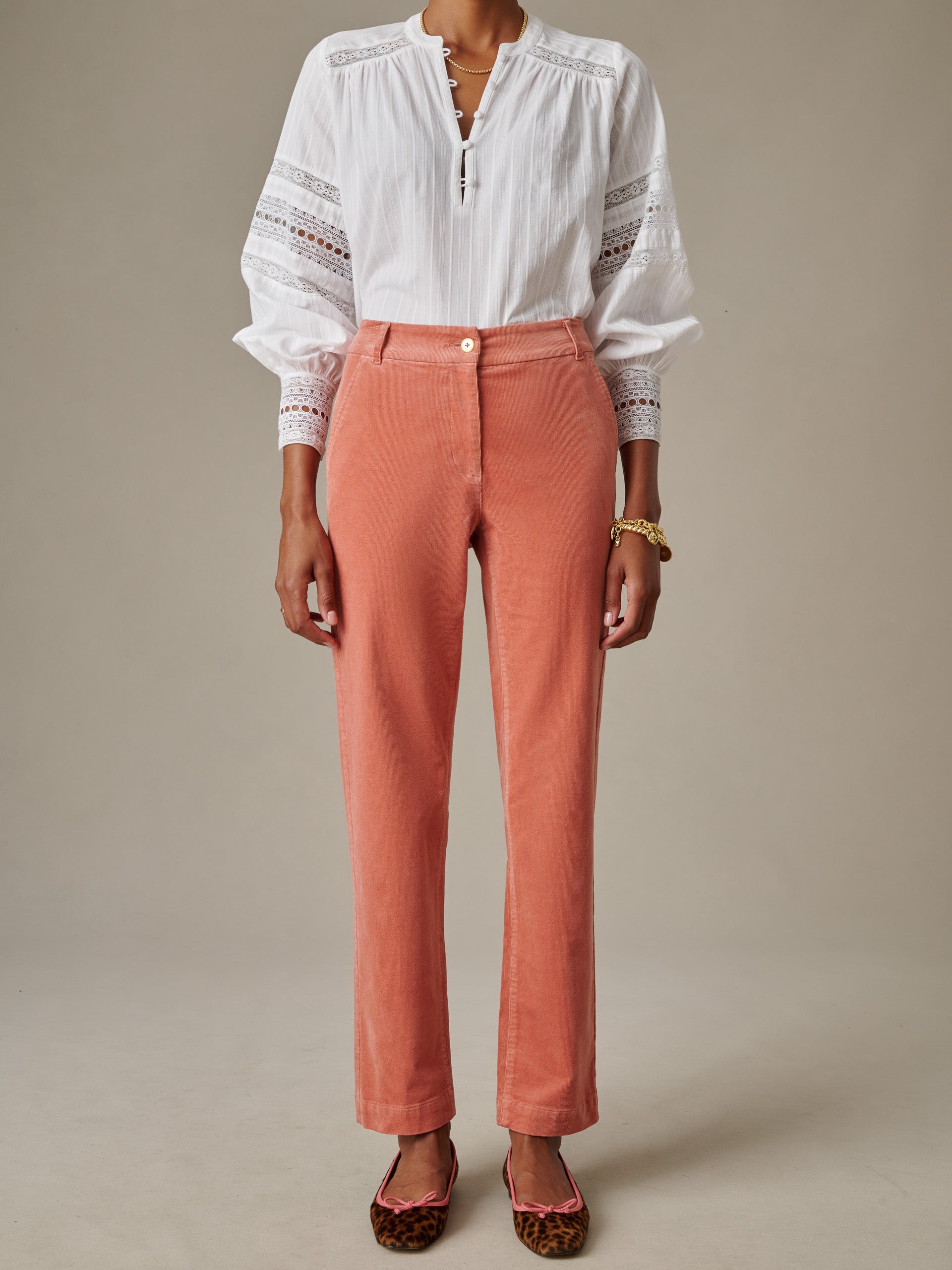A model wearing coral Avery Corduroy Pants by J.McLaughlin paired with a white blouse and leopard print flats, showcasing an effortlessly stylish and timeless look.