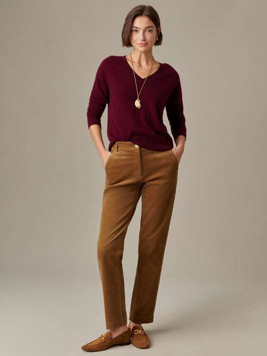 Woman wearing Avery Corduroy Pants by J.McLaughlin in a warm brown shade paired with a deep burgundy sweater and loafers, showcasing an effortlessly stylish, timeless look.