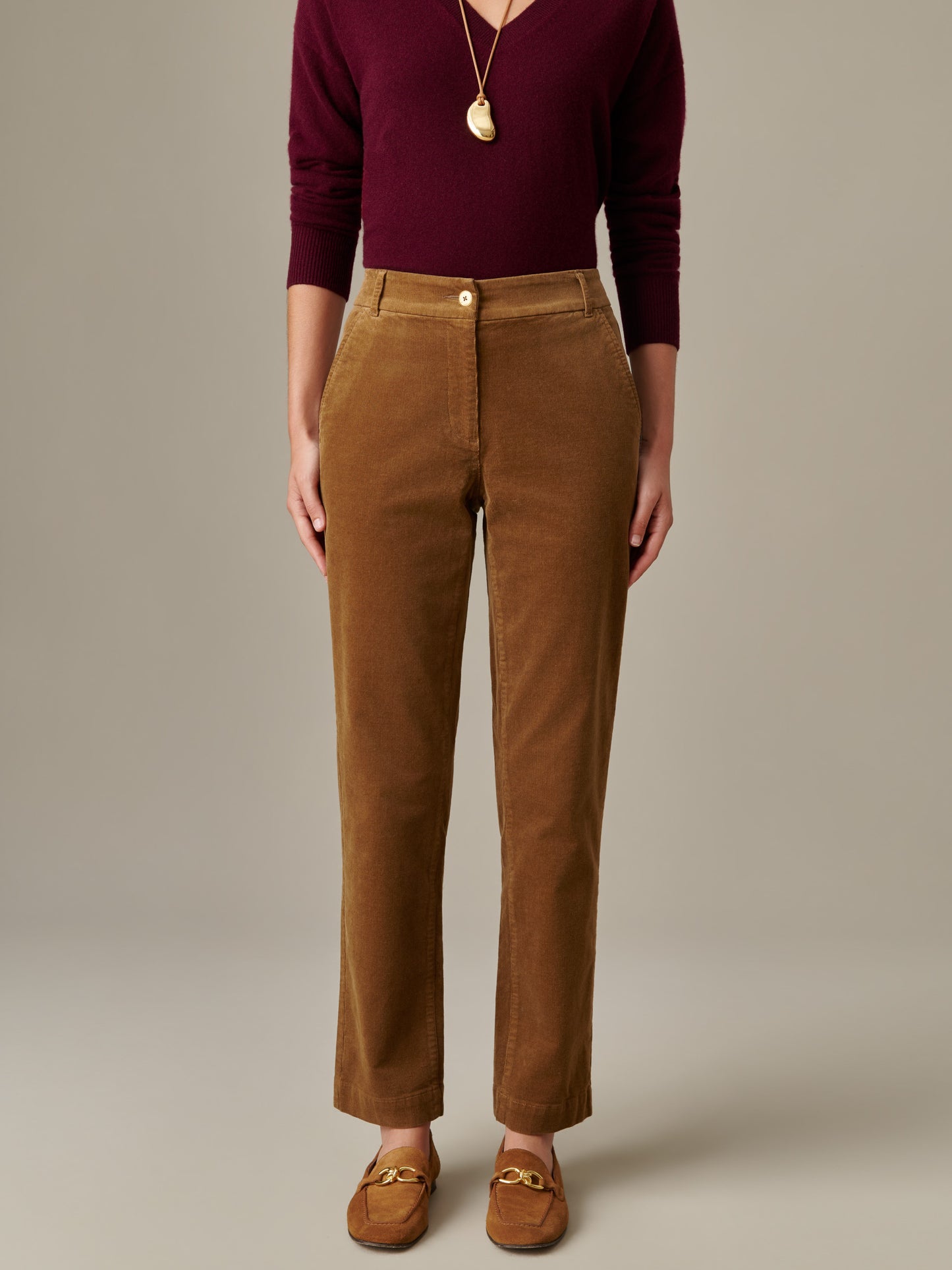 Front view of a person wearing brown Avery Corduroy Pants by J.McLaughlin paired with a burgundy long-sleeve top and brown loafers, showcasing an effortlessly stylish and timeless look.