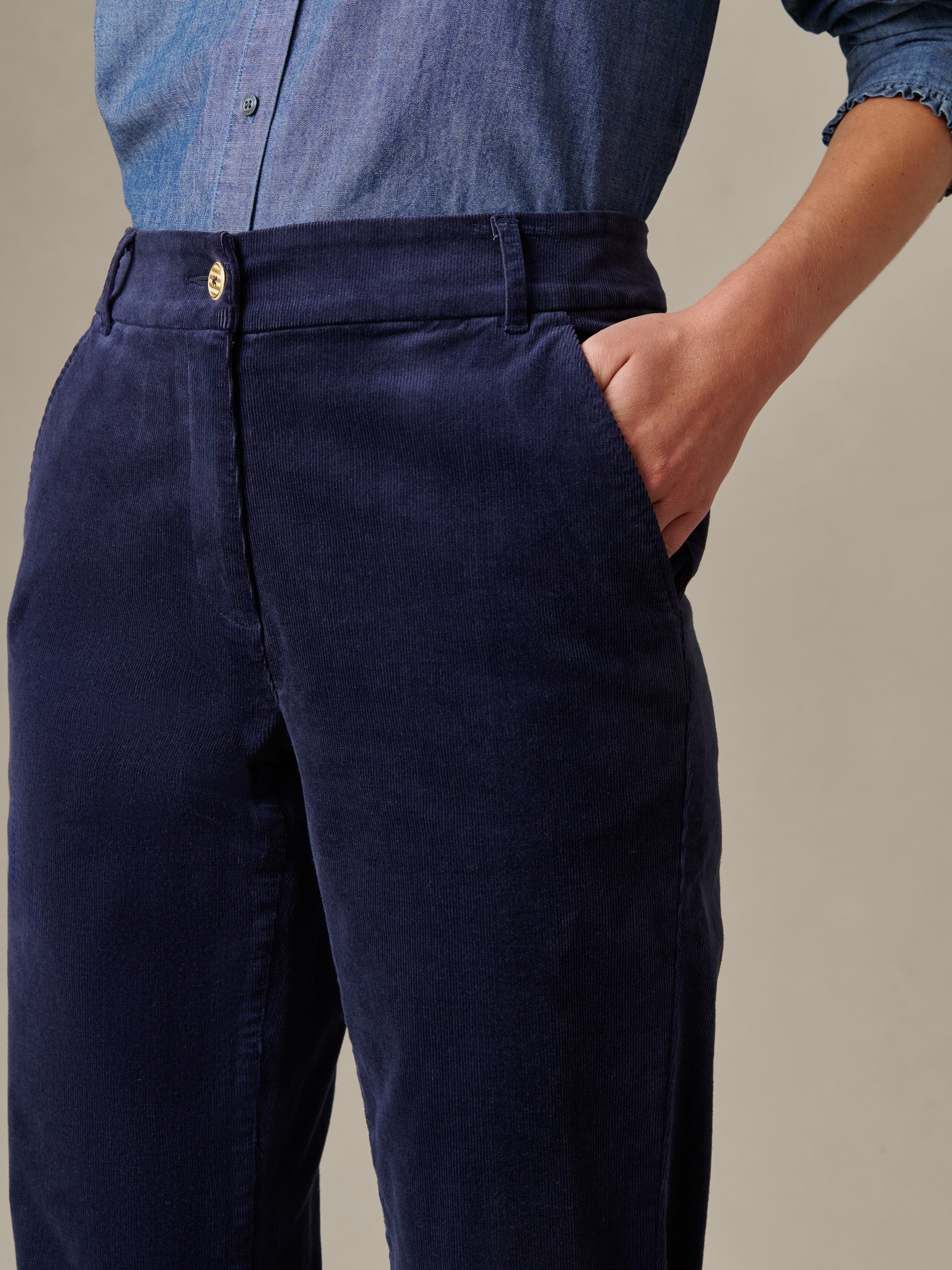 Close-up of a person wearing deep navy Avery Corduroy Pants by J.McLaughlin with a tucked-in chambray shirt, showcasing the tailored fit and classic style.