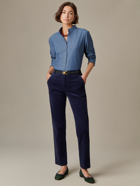 Woman wearing Avery Corduroy Pants by J.McLaughlin in navy blue, paired with a light blue button-up shirt, black belt, and green flats, showcasing timeless, enduring design.