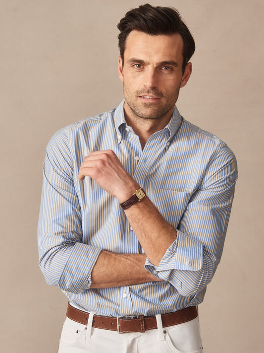 Man wearing a Belvedere Cotton Shirt in Multi Stripe by J.McLaughlin, paired with white pants and a brown leather belt, showcasing effortlessly stylish, enduring designs with innovative fabrics.