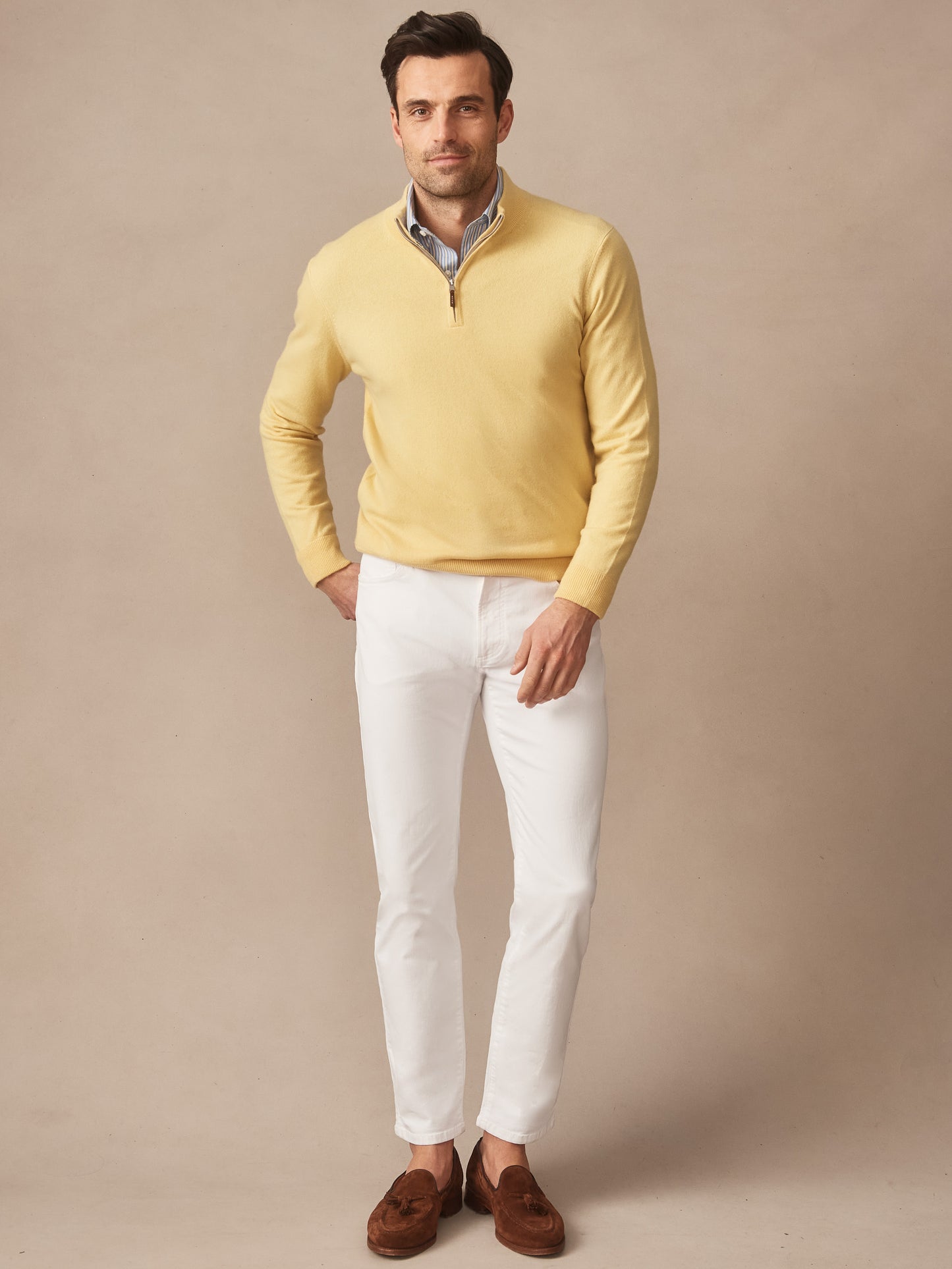 Man wearing a yellow Twain Cashmere 1/4 Zip sweater from J.McLaughlin paired with white pants and brown loafers, showcasing effortlessly stylish, enduring designs and innovative fabrics.