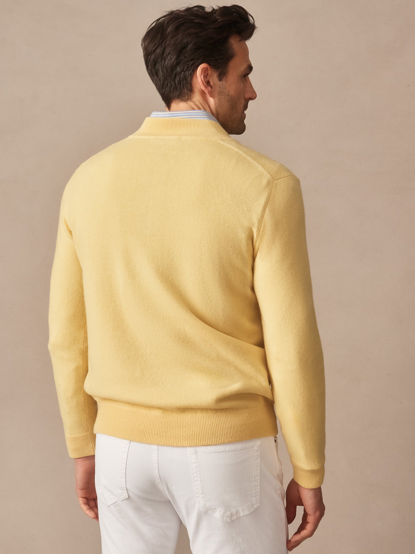 Man wearing a pale yellow Twain Cashmere 1/4 Zip sweater by J.McLaughlin, paired with white pants, showcasing effortlessly stylish, enduring designs and innovative fabrics.