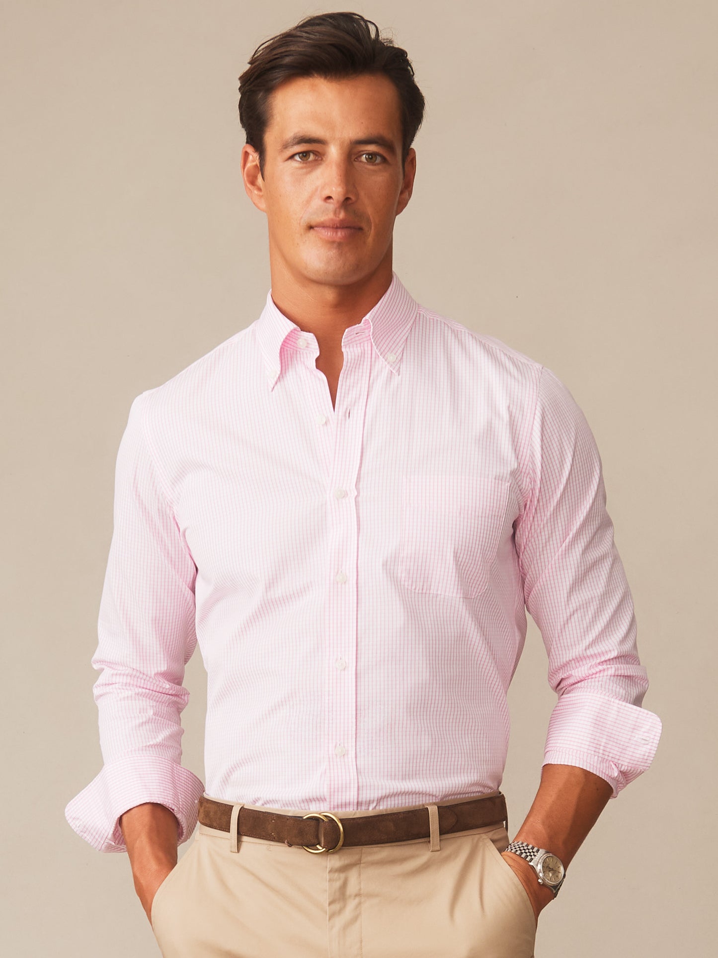 Man wearing a Belvedere Cotton Shirt in Graphic Check by J.McLaughlin, featuring effortlessly stylish pink check pattern, paired with beige pants and a brown belt, embodying enduring designs and a legacy of timeless fashion. A destination for defining style. Life, Well-Lived.