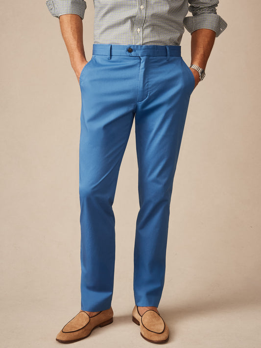 Man wearing blue Madison Pants by J.McLaughlin paired with a checked shirt and tan suede loafers, showcasing effortlessly stylish, enduring designs and innovative fabrics.