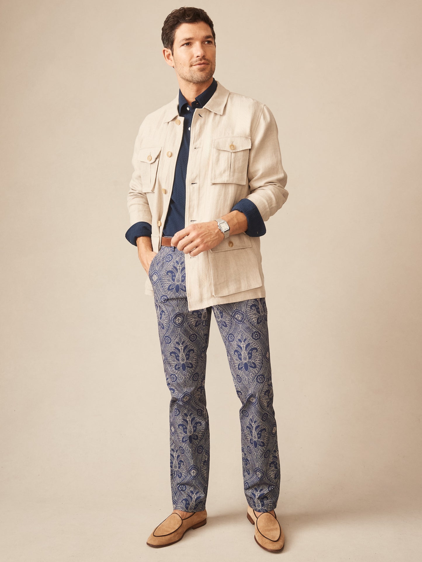 Man wearing J.McLaughlin Madison Fancy Pants in Baroque Hall with a navy shirt and beige jacket, showcasing effortlessly stylish pants with enduring designs, a destination for defining style. Life, Well-Lived.