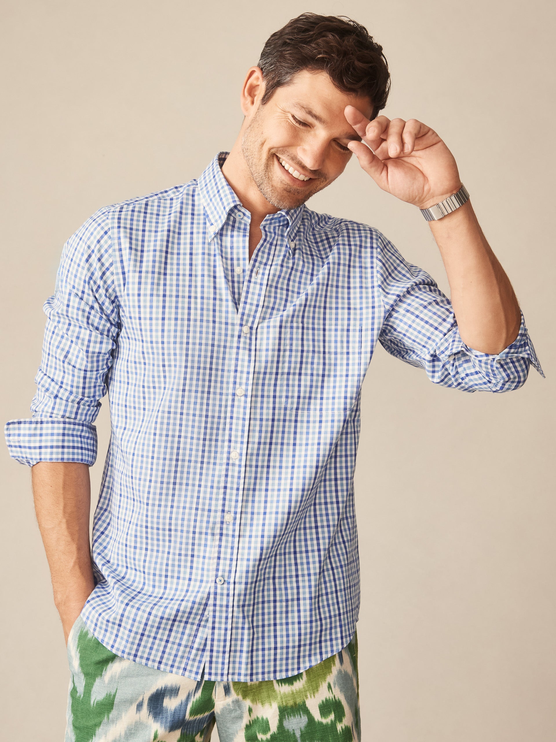 A man wearing the Belvedere Cotton Shirt in Gingham Multi by J.McLaughlin, showcasing an effortlessly stylish, classic blue and white gingham pattern that reflects enduring designs and a legacy of timeless fashion.