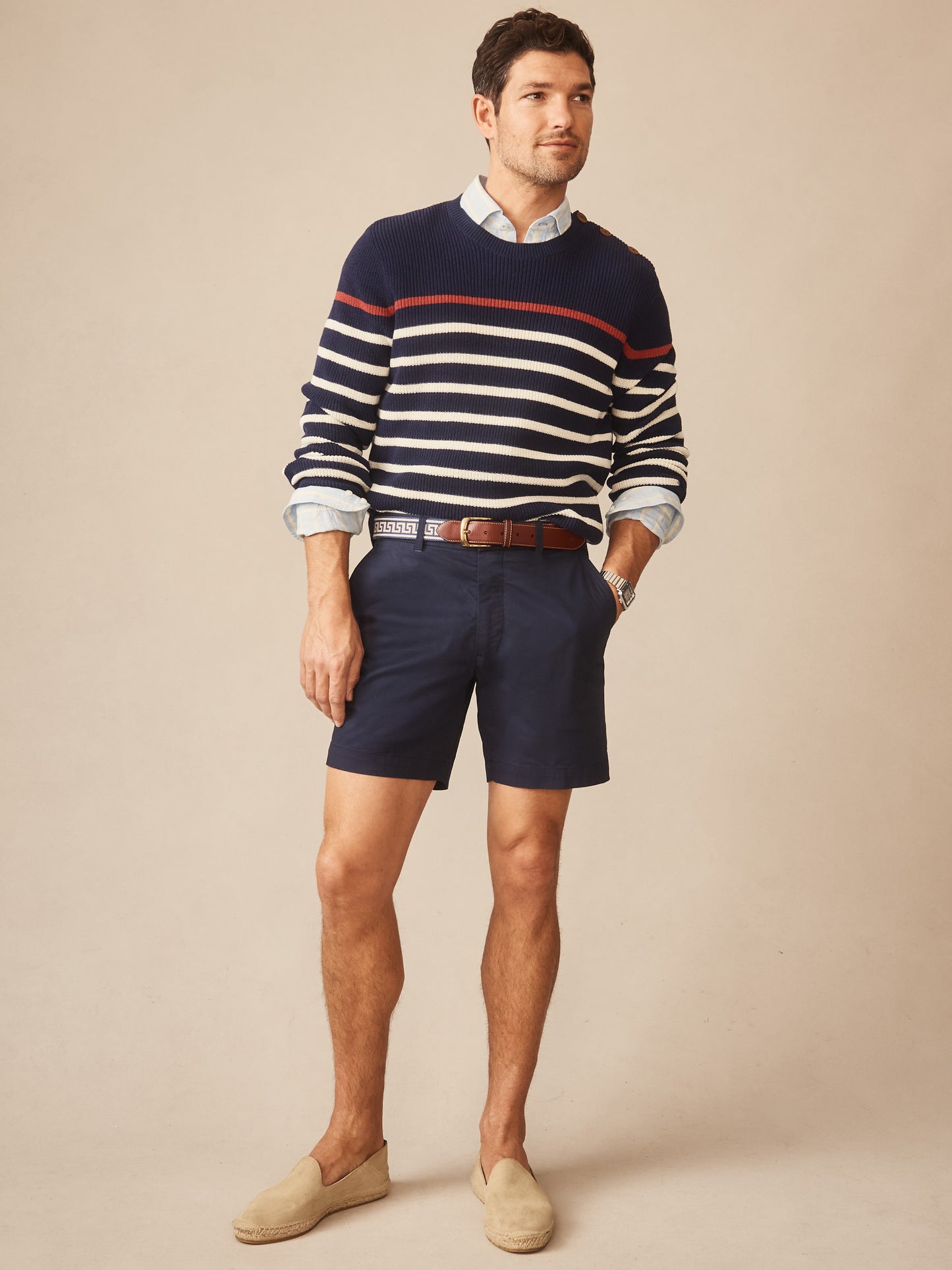 Man wearing a Bennett Sweater in Stripe by J.McLaughlin, styled with navy shorts and casual espadrilles, showcasing effortlessly stylish, enduring designs and innovative fabrics.