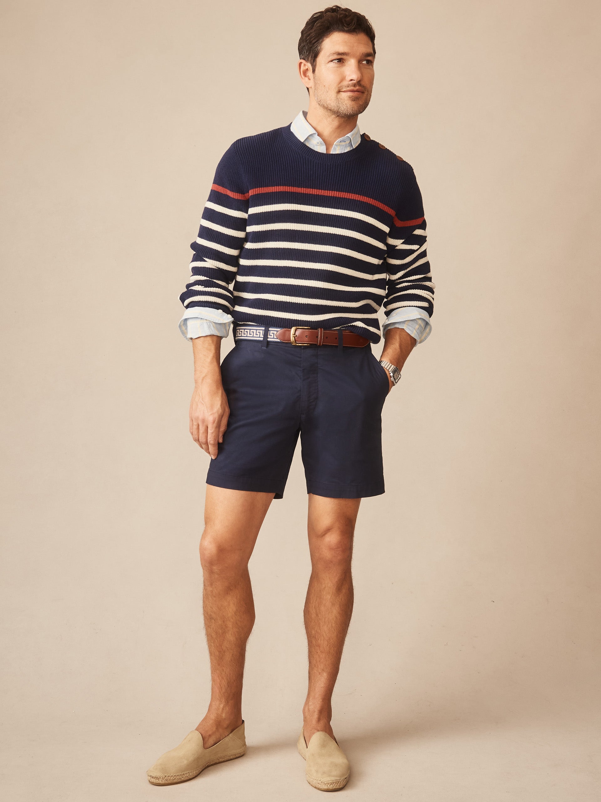 Man wearing a Bennett Sweater in Stripe by J.McLaughlin, styled with navy shorts and casual espadrilles, showcasing effortlessly stylish, enduring designs and innovative fabrics.