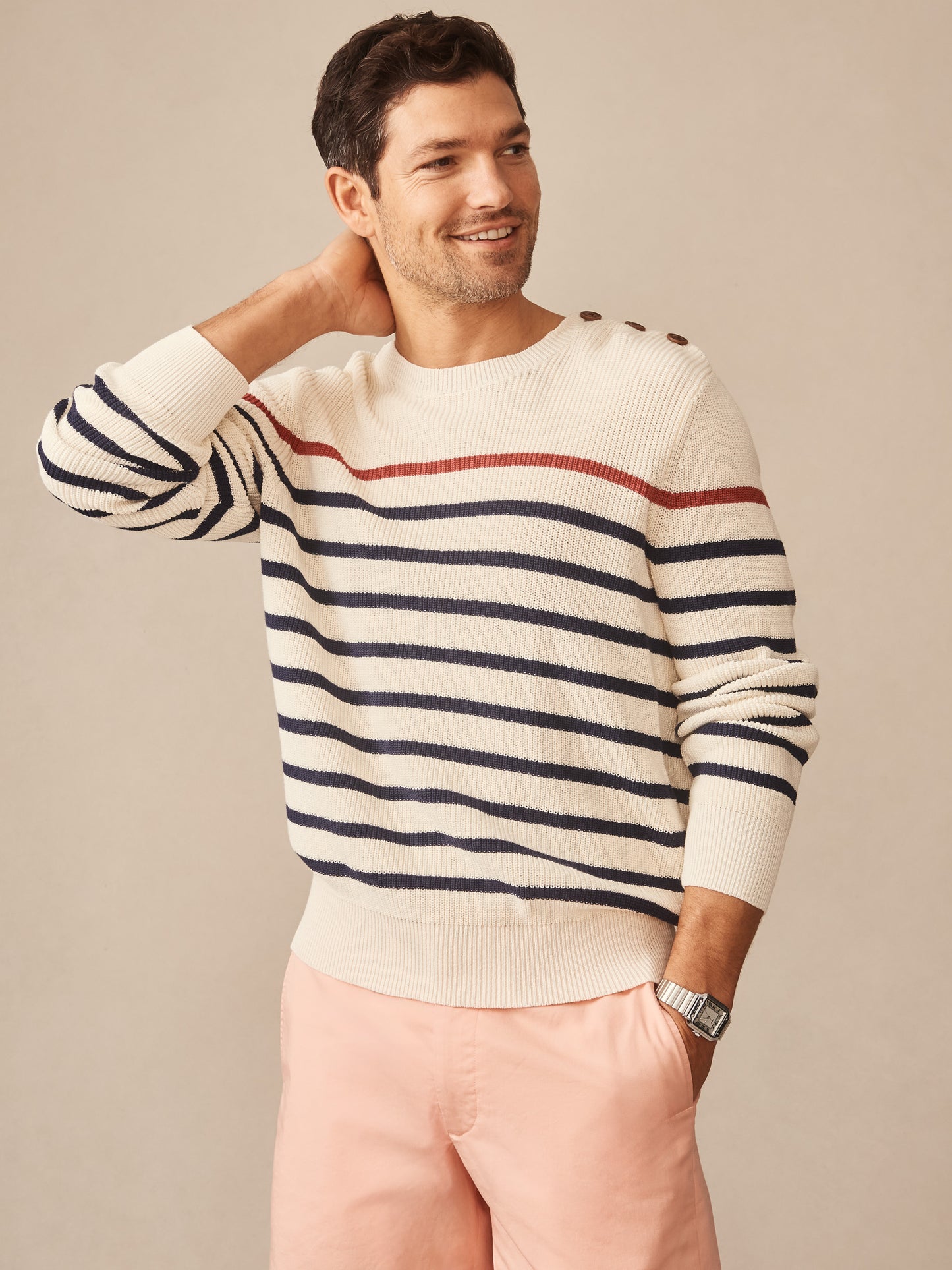 Man wearing J.McLaughlin Bennett Sweater in Stripe with navy and rust stripes on cream, paired with light pink shorts, showcasing effortlessly stylish, enduring designs and innovative fabrics in a legacy of timeless fashion. A destination for defining style. Life, Well-Lived.
