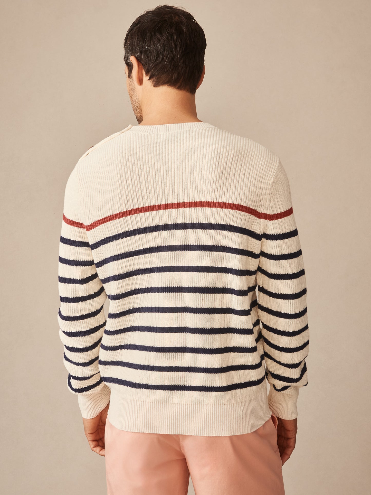 Back view of a man wearing the Bennett Sweater in Stripe by J.McLaughlin, featuring navy and rust horizontal stripes on an off-white knit, combining innovative fabrics with enduring designs for effortlessly stylish, timeless fashion.