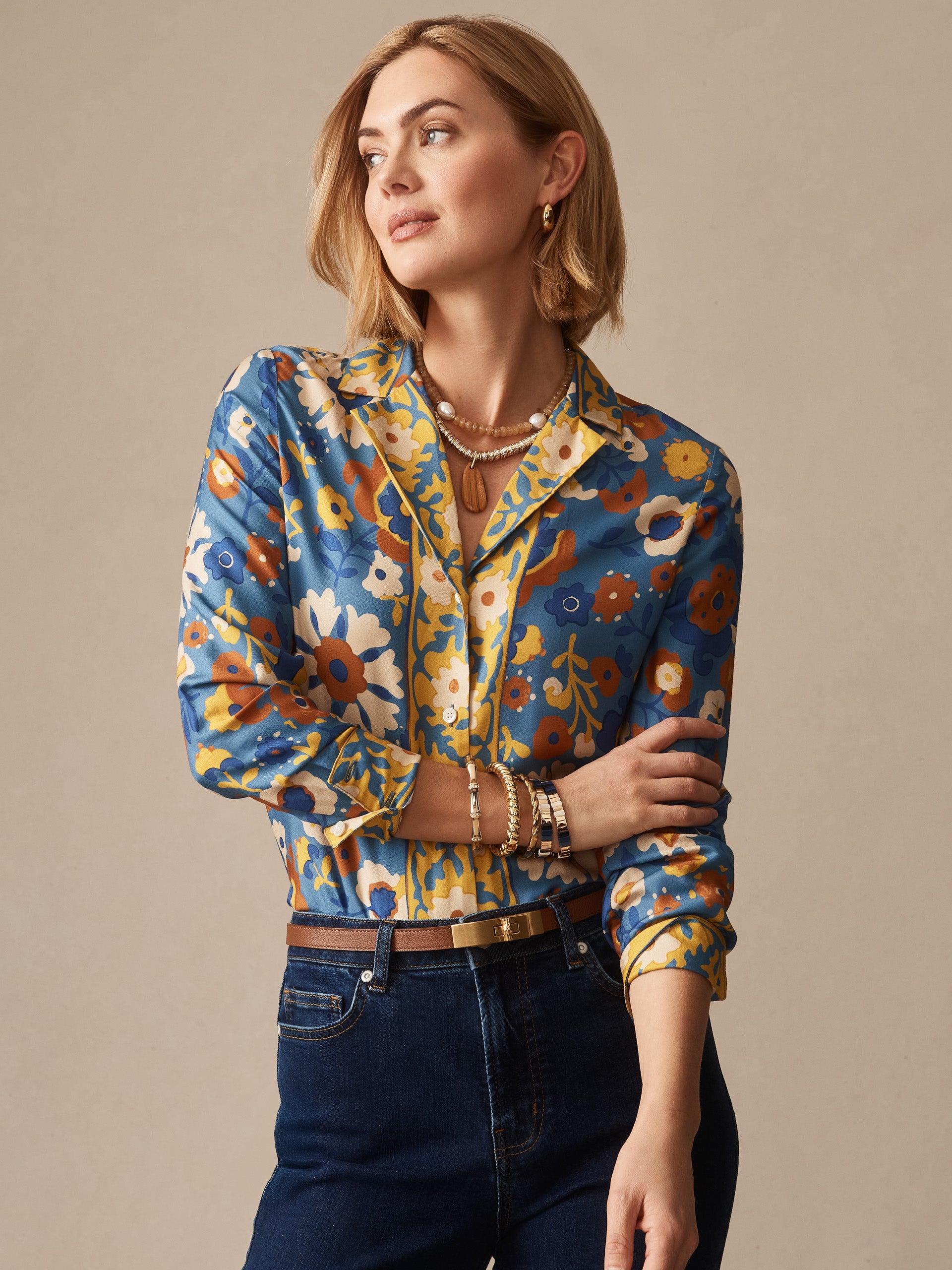 Woman modeling the Bimini Shirt in Floral Daydream Edge by J.McLaughlin, featuring a floral print in blue, yellow, and brown tones, showcasing effortlessly stylish, enduring designs with innovative fabrics in a legacy of timeless fashion. A destination for defining style. Life, Well-Lived.