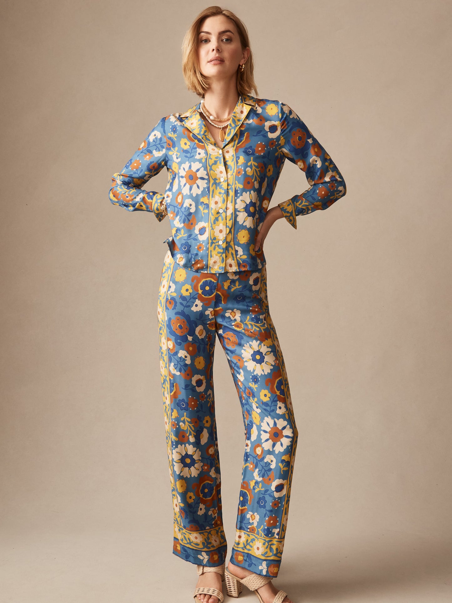 A confident woman wearing the Bimini Shirt in Floral Daydream Edge by J.McLaughlin, featuring effortlessly stylish floral patterns in blue, yellow, and brown tones, embodying enduring designs and innovative fabrics—a destination for defining style. Life, Well-Lived.