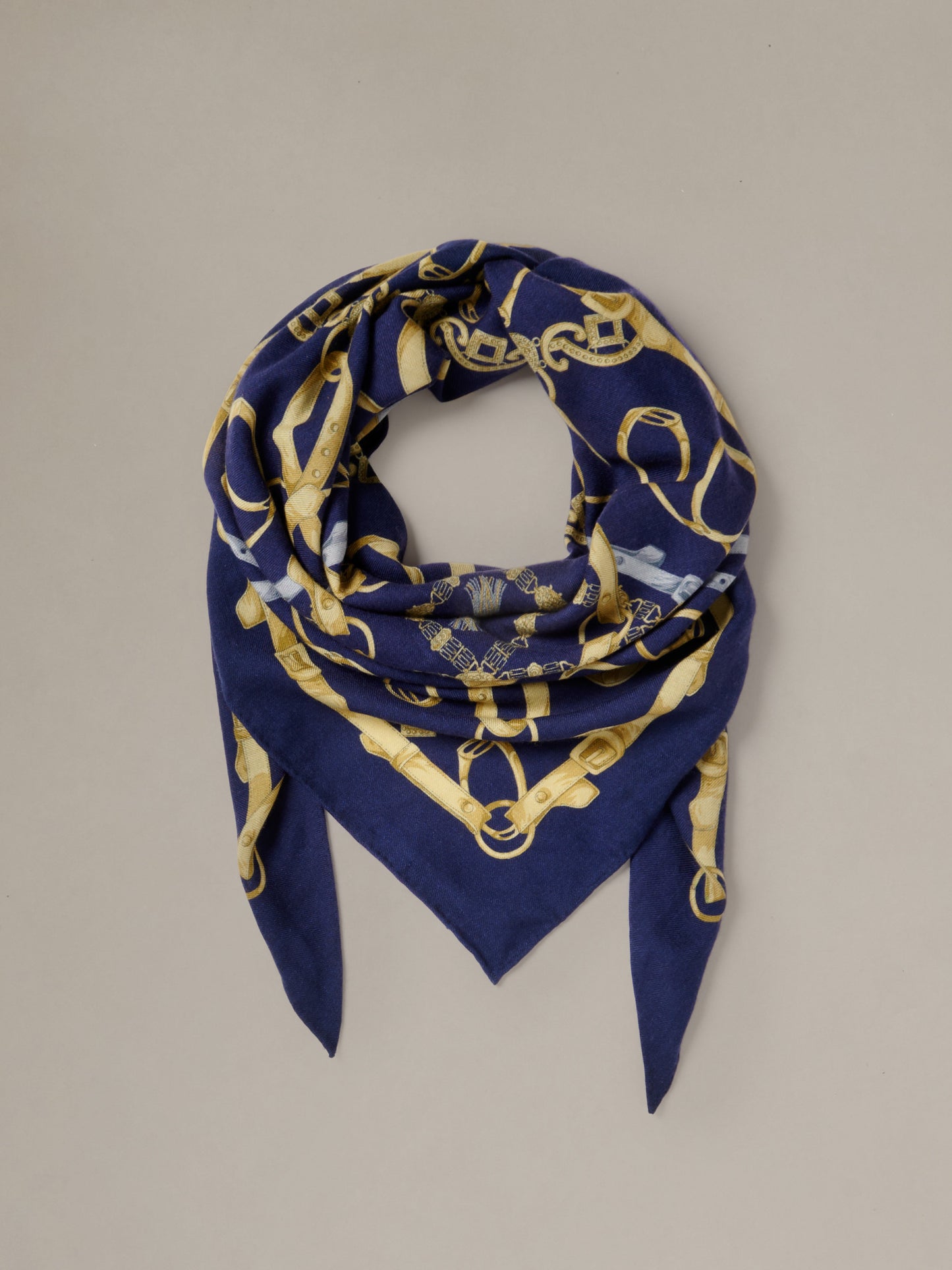The Blair Scarf in Grand Heraldic Corner by J.McLaughlin shown as a navy and gold patterned triangular scarf styled in a soft loop with pointed ends