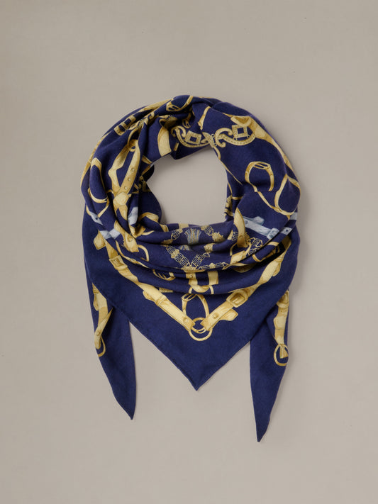 The Blair Scarf in Grand Heraldic Corner by J.McLaughlin shown as a navy and gold patterned triangular scarf styled in a soft loop with pointed ends