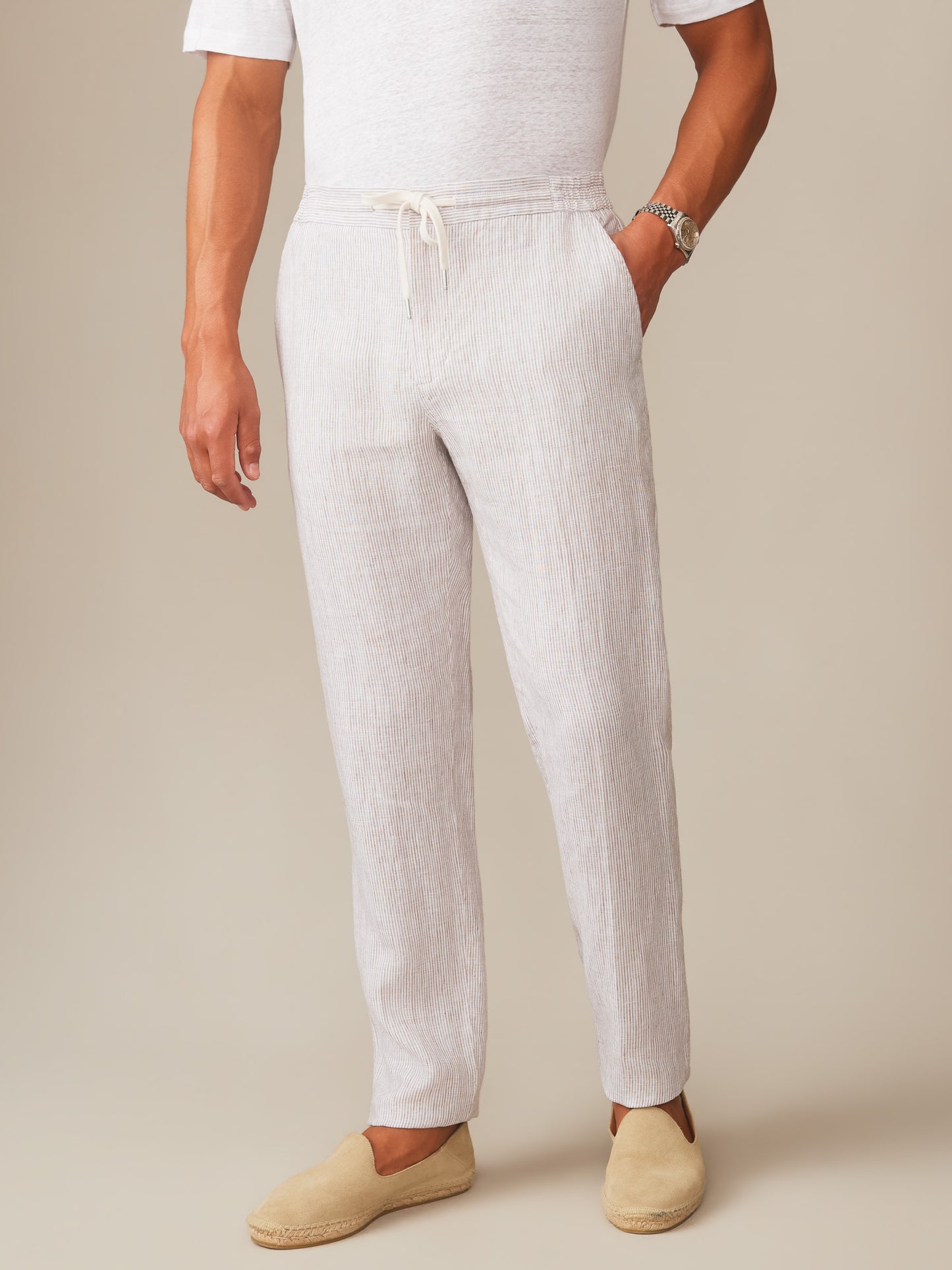 Man wearing Bleeker Linen Fancy Pants in Hairline Stripe by J.McLaughlin paired with casual beige slip-on shoes, showcasing effortlessly stylish, enduring designs in innovative fabrics.