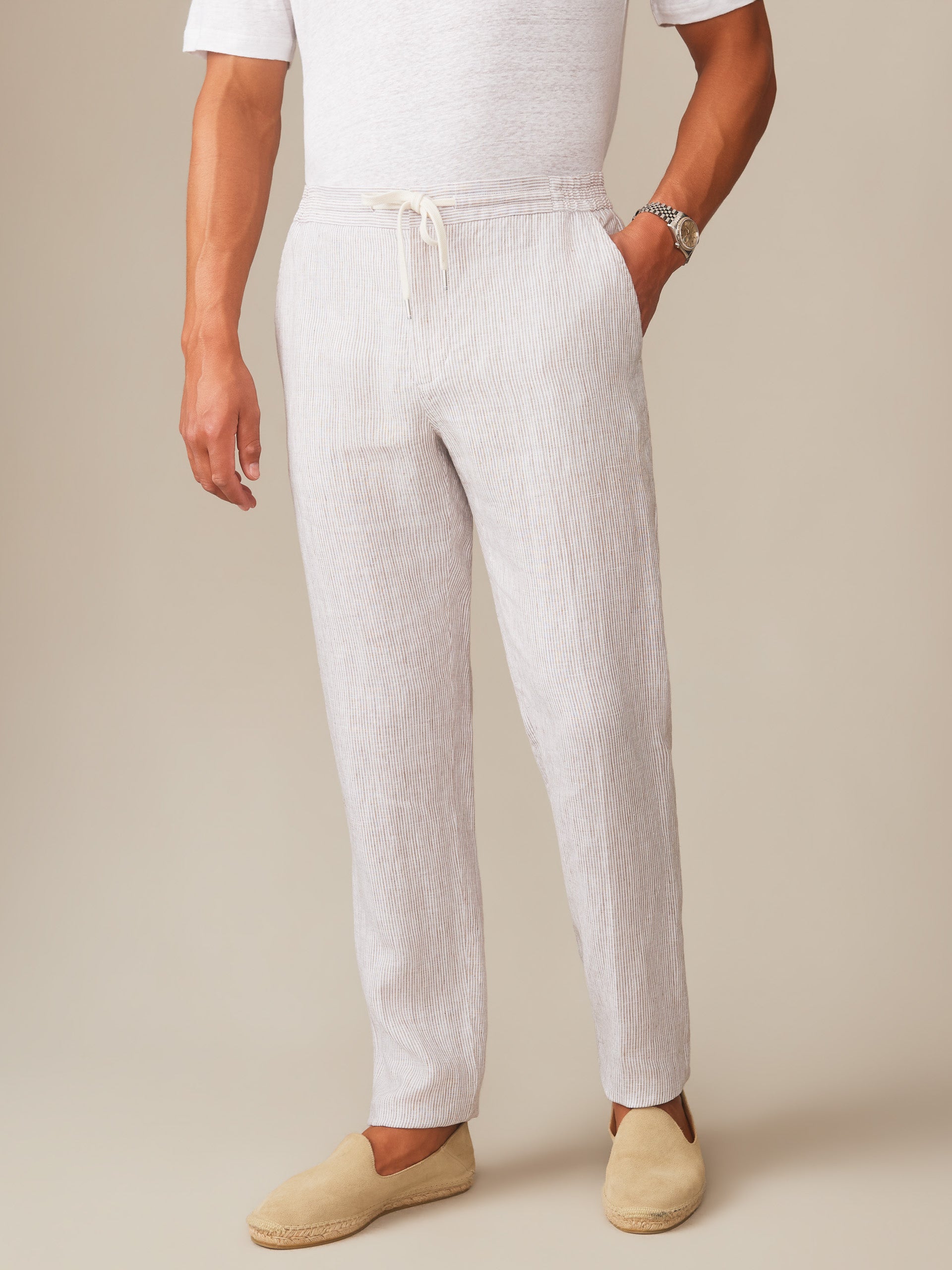 Man wearing Bleeker Linen Fancy Pants in Hairline Stripe by J.McLaughlin paired with casual beige slip-on shoes, showcasing effortlessly stylish, enduring designs in innovative fabrics.