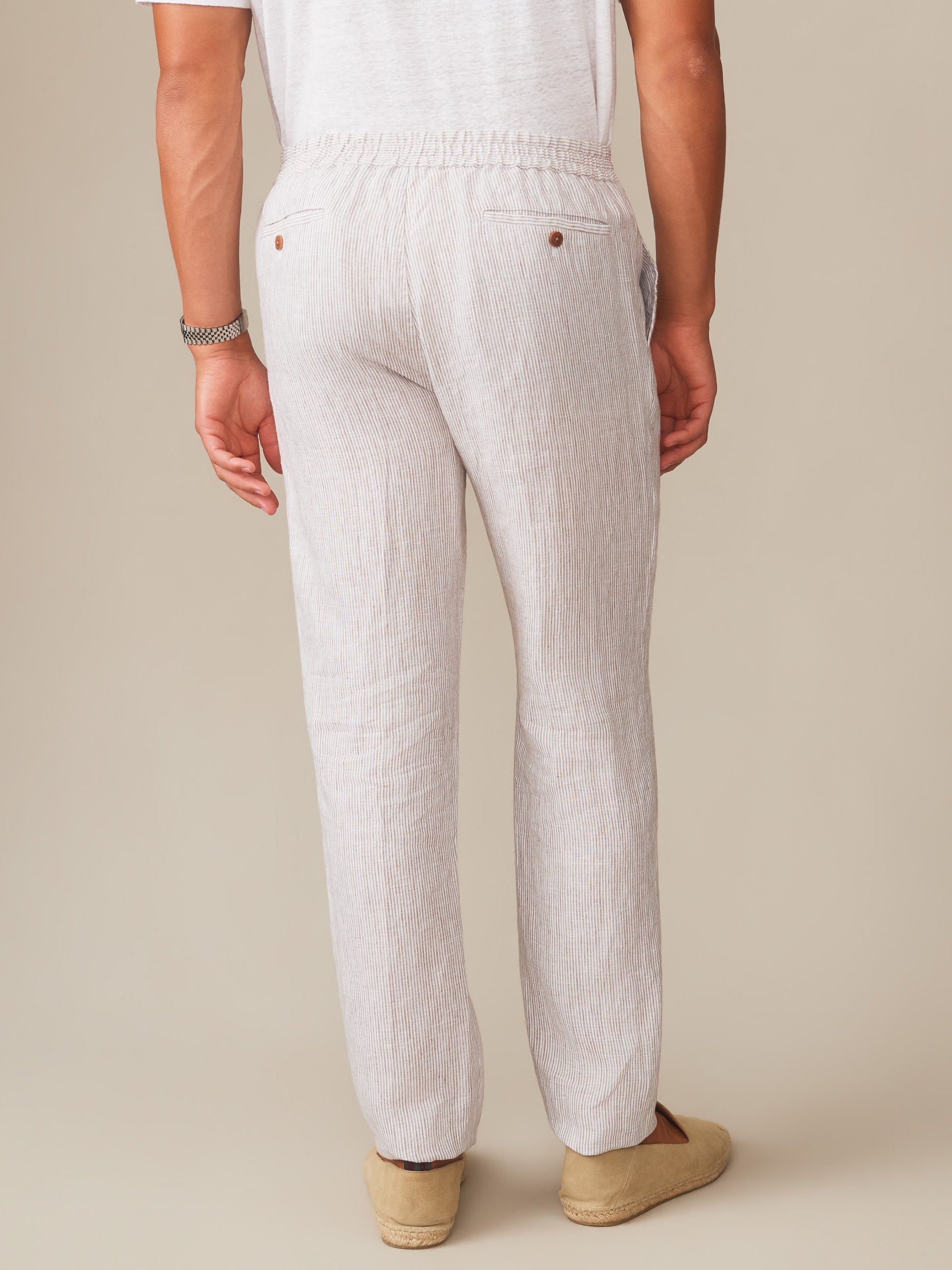 Rear view of a man wearing Bleeker Linen Fancy Pants in Hairline Stripe by J.McLaughlin, showcasing effortlessly stylish pants designed with innovative fabrics for enduring designs.