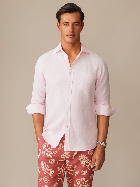 A male model wears the Gramercy Linen Shirt in soft pink by J.McLaughlin, paired with patterned pants, reflecting effortlessly stylish, enduring designs and a legacy of timeless fashion.