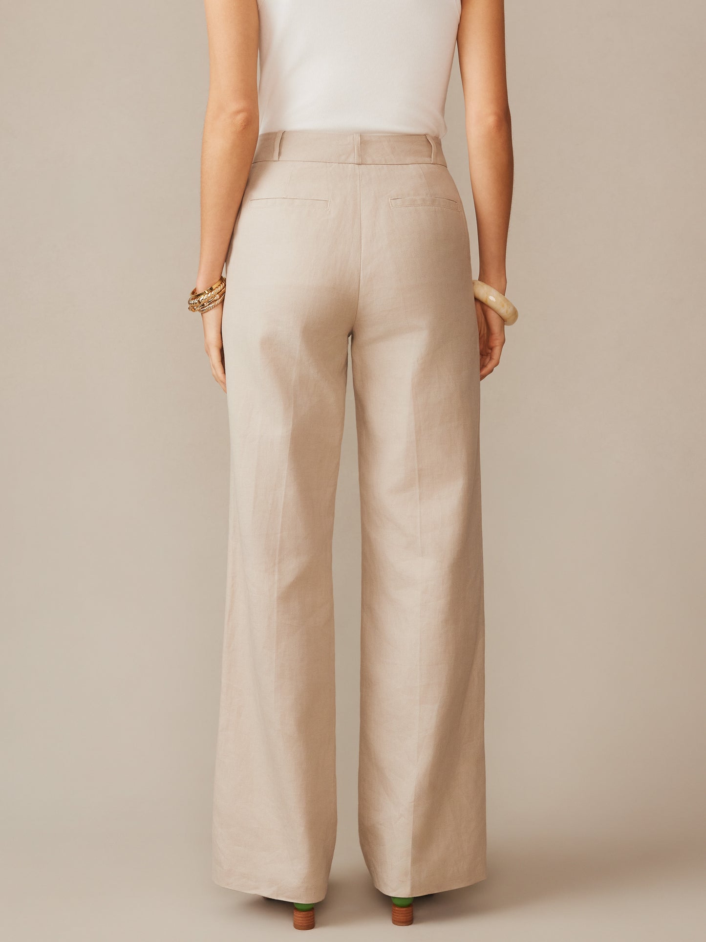 A woman wears Blythe Linen Blend Pants in a neutral sand tone by J.McLaughlin, showcasing effortlessly stylish pants that embody enduring designs and a legacy of timeless fashion.