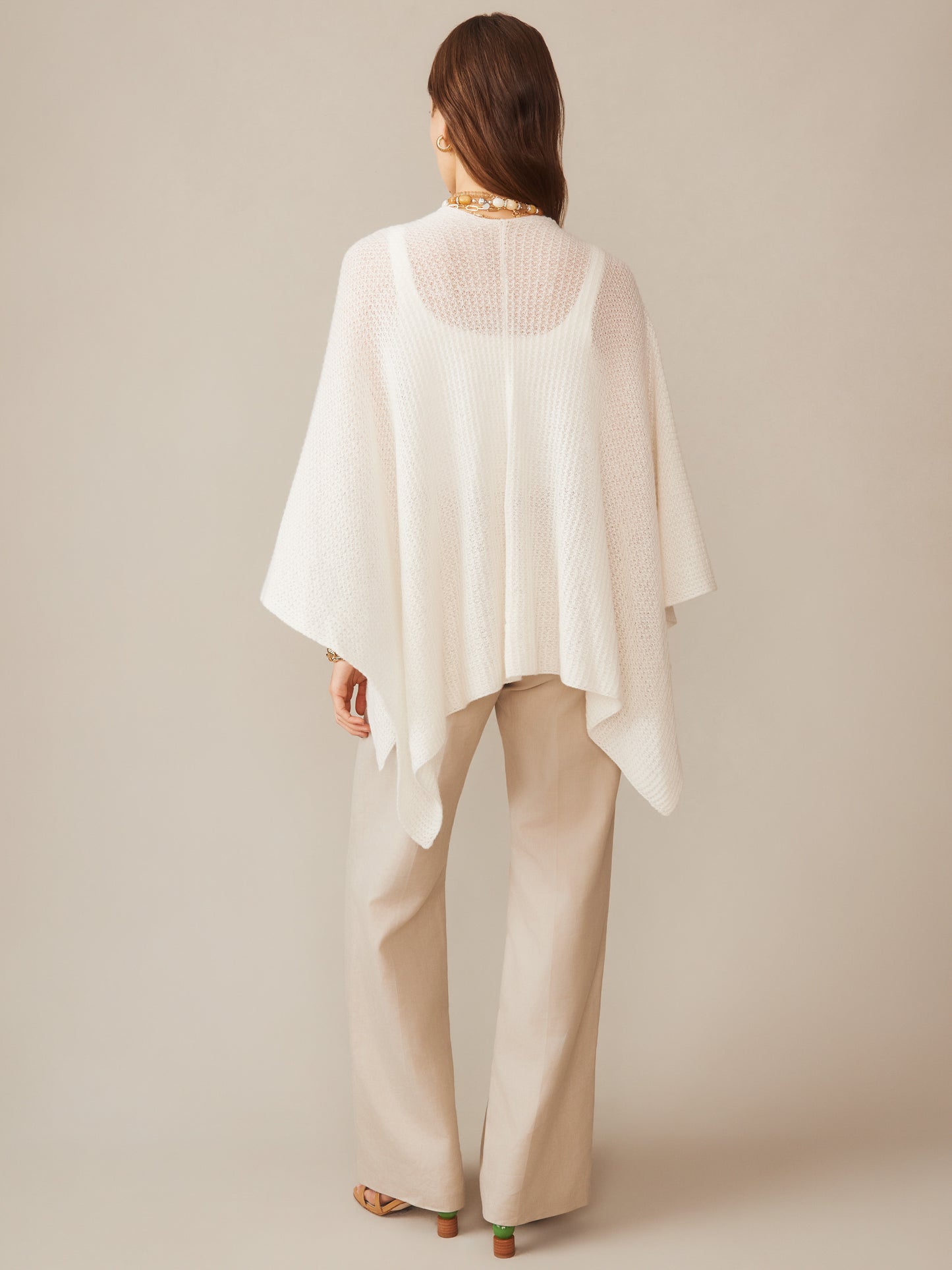 Woman seen from behind wearing a white Julianne Cashmere Wrap by J.McLaughlin paired with beige pants, showcasing effortlessly stylish, enduring designs with a legacy of timeless fashion.